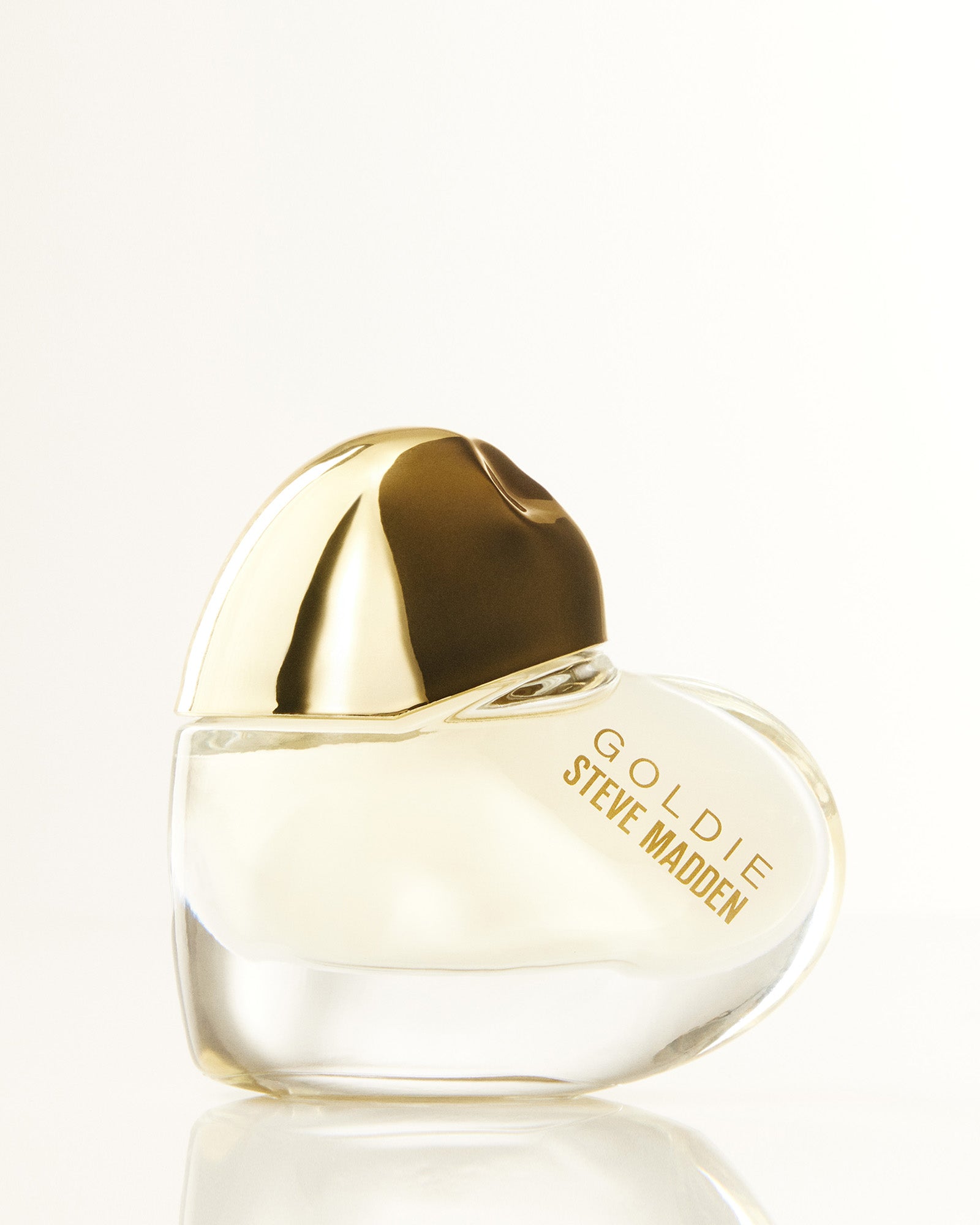 Close-up of Goldie Radiant Mini perfume bottle with soft floral lighting