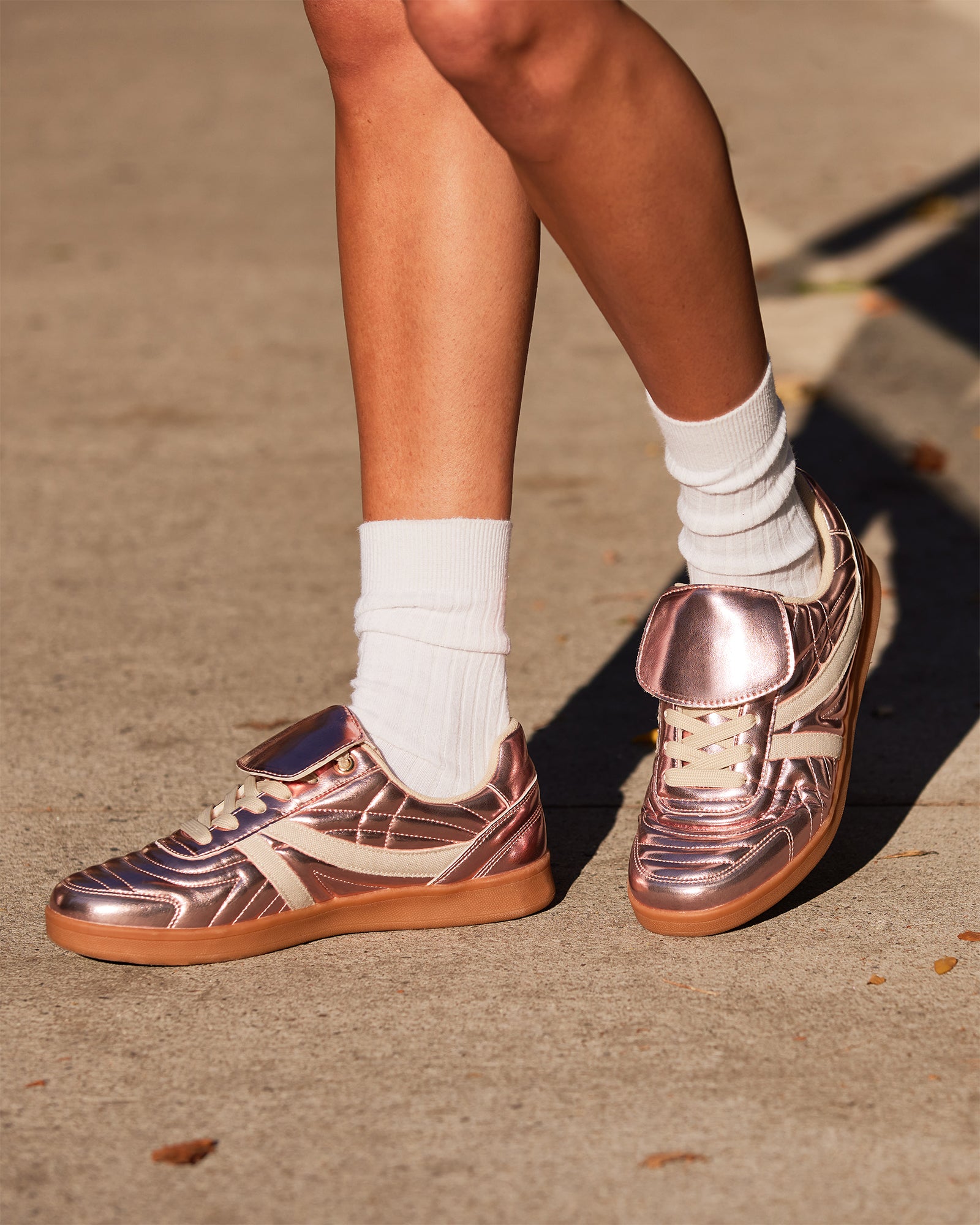Side view of Bottega Madrid pink metallic sneakers on a wooden surface