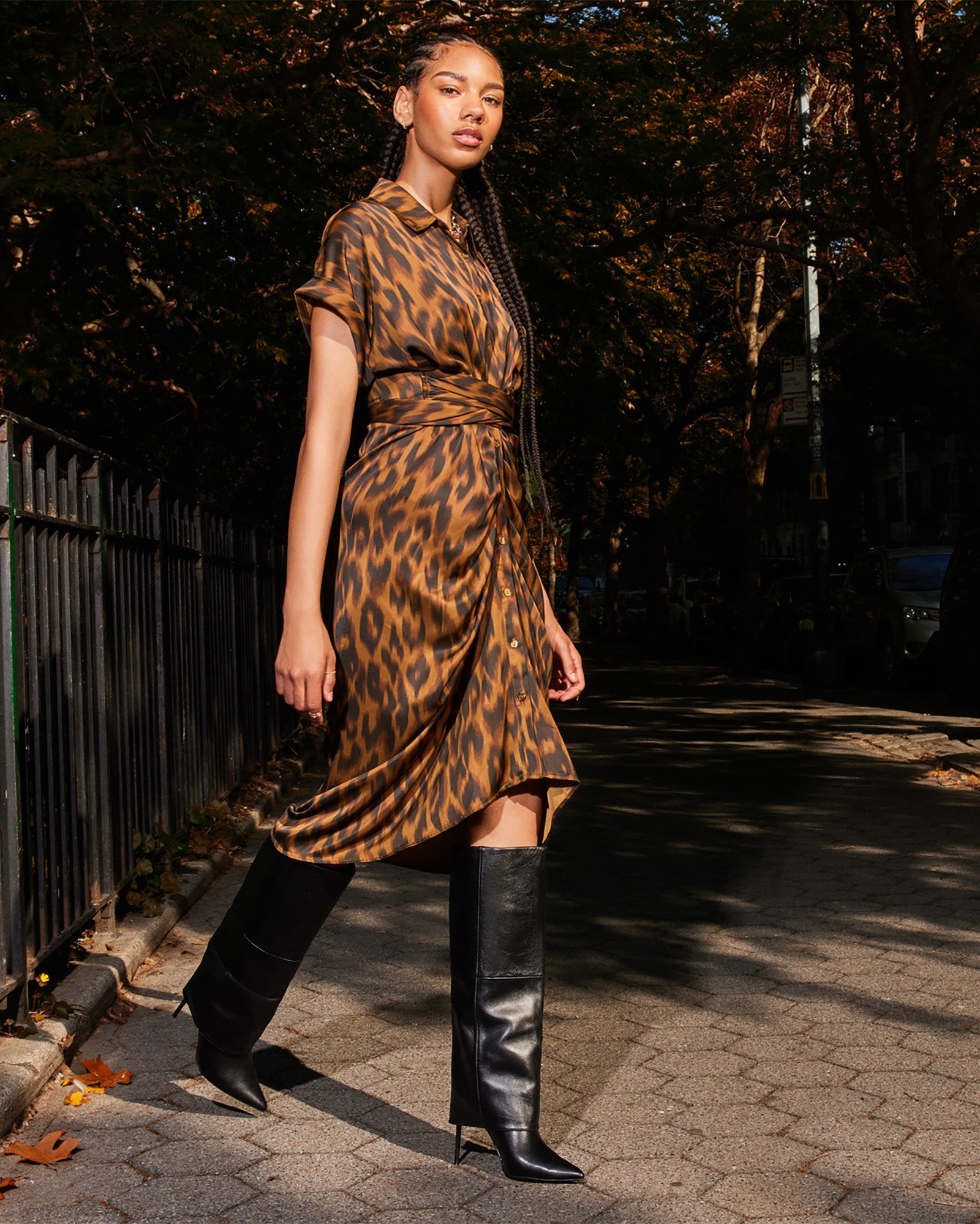 Model wearing black satin dress with high-low hem at outdoor café