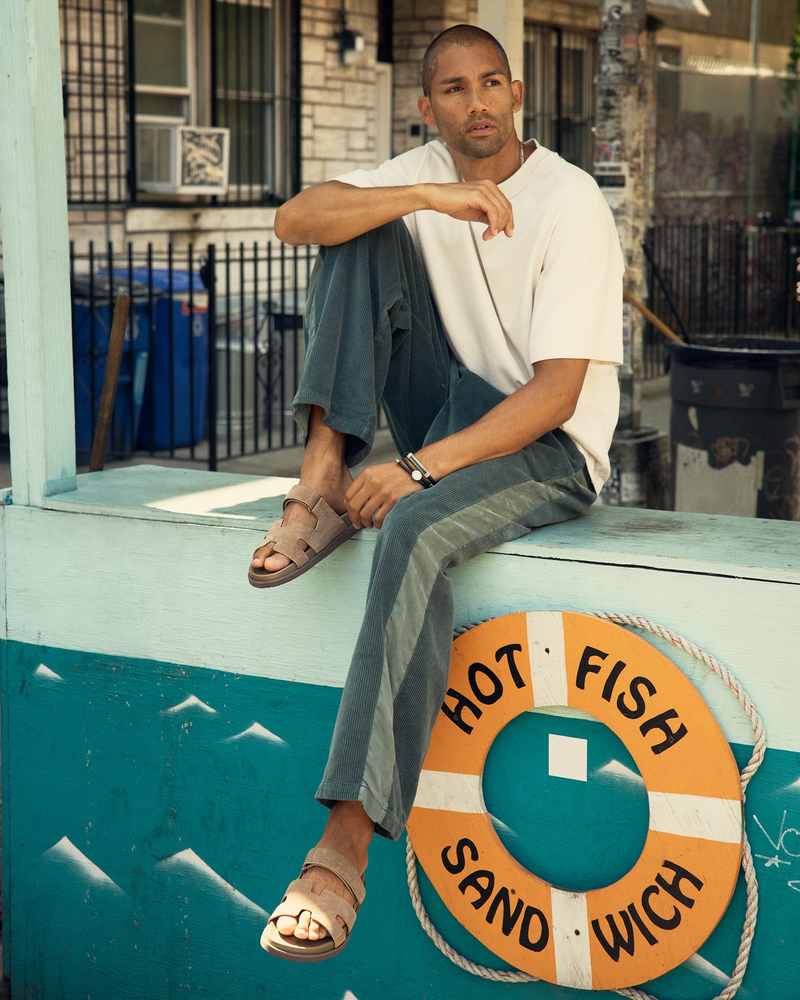 Model wearing taupe suede slides at a summer beach party, demonstrating versatility.