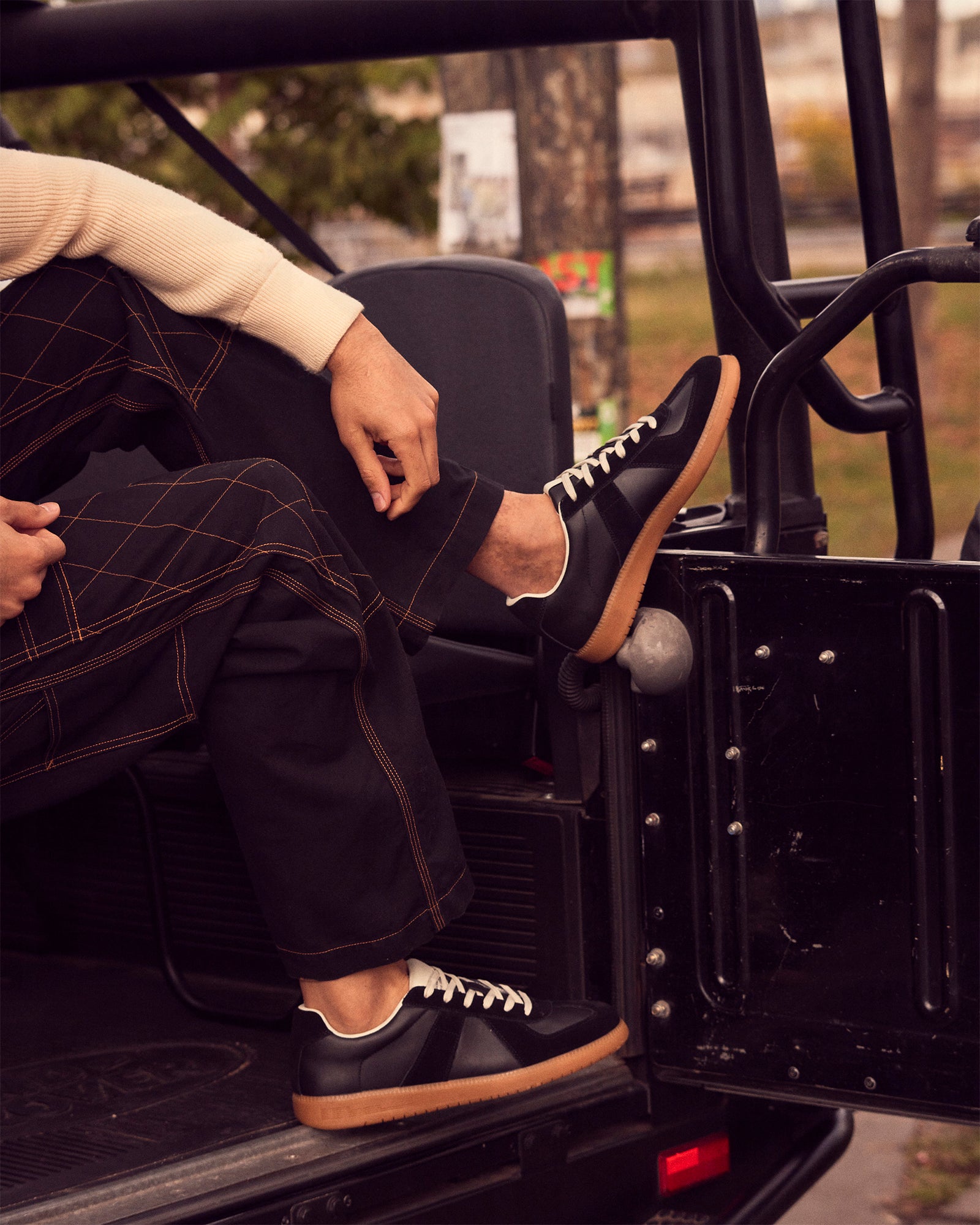 Black leather low-top sneakers with lace-up closure on a casual outfit
