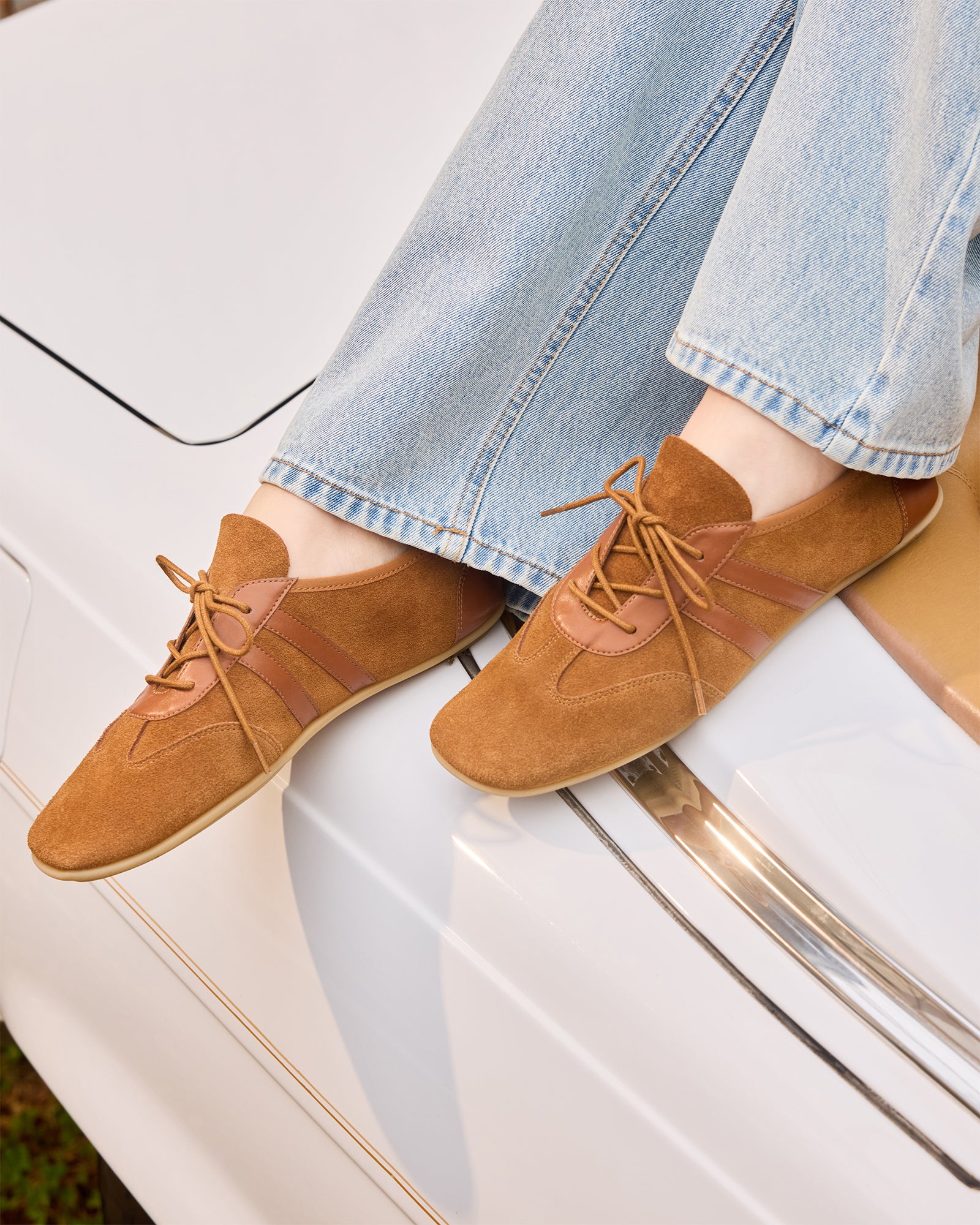 Close-up of the lace-up feature on chestnut suede sneakers, perfect for everyday wear.