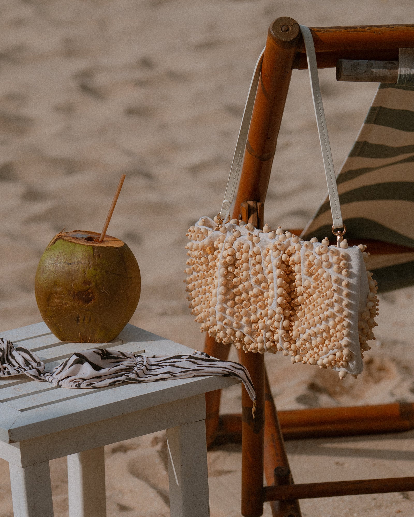 Tiki wristlet bag displayed on a sandy beach, ideal for summer.