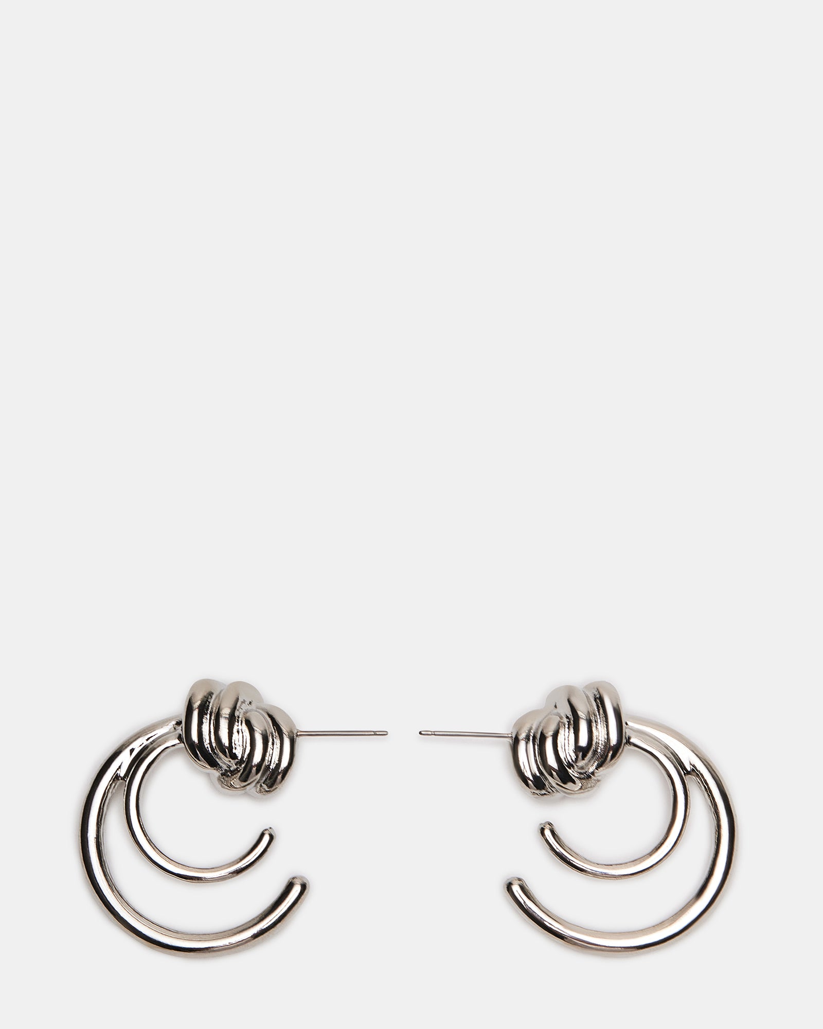 Close-up of silver hoop earrings with modern knot accent, resting on suede pouch.