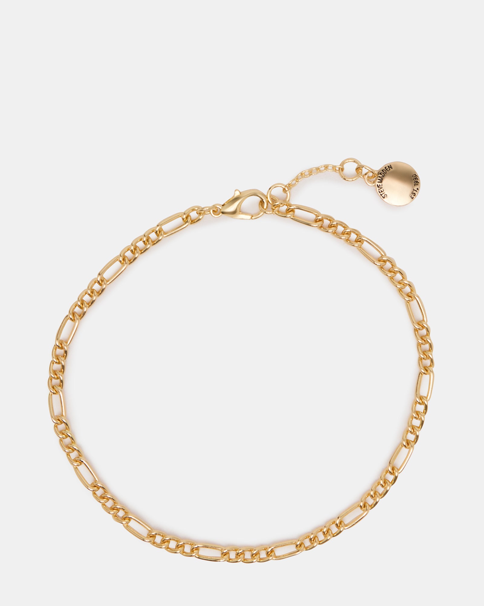 Close-up of a gold anklet with Figaro chain design on a model's ankle