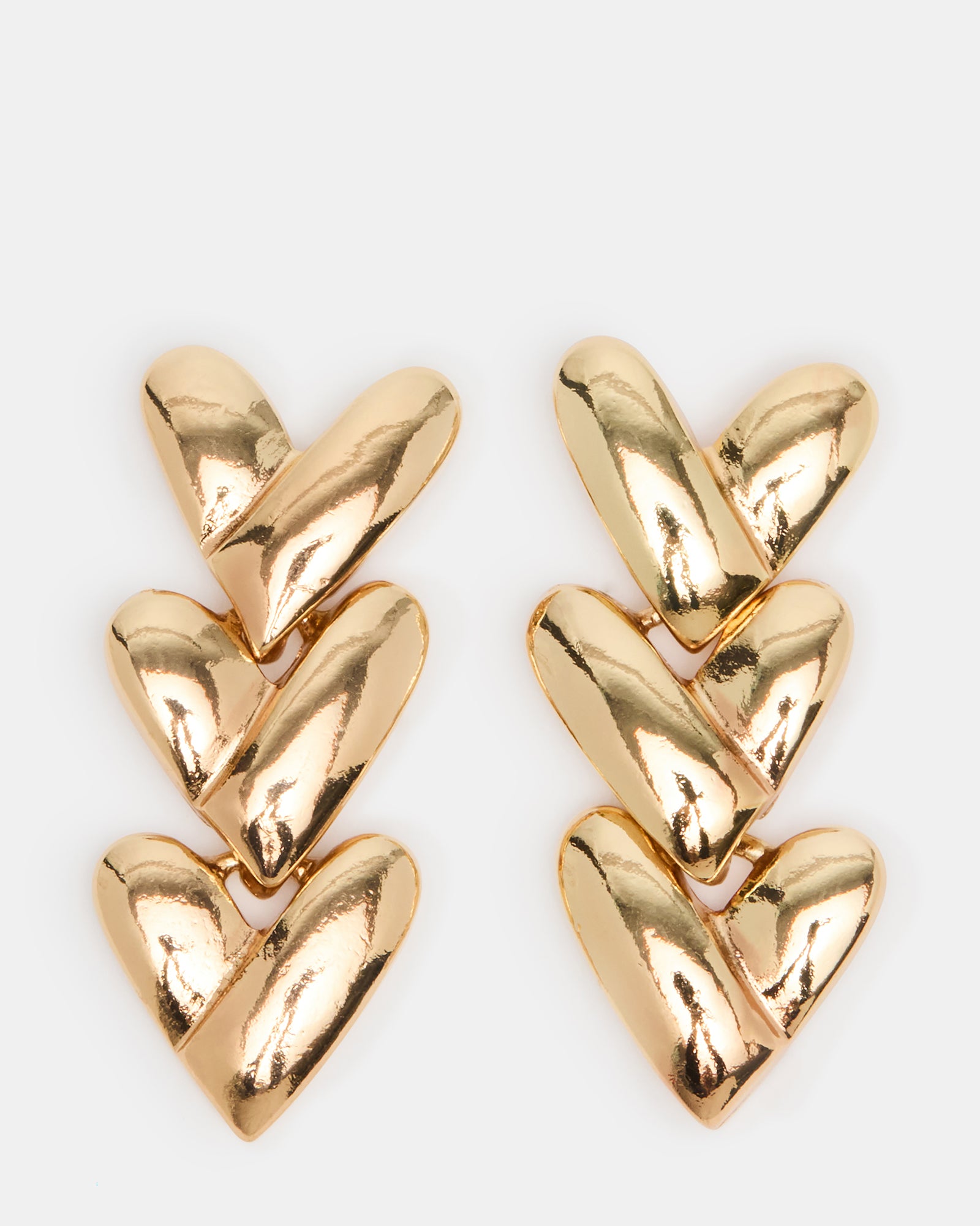 Close-up of 14k gold heart earrings with linear detailing on a velvet tray