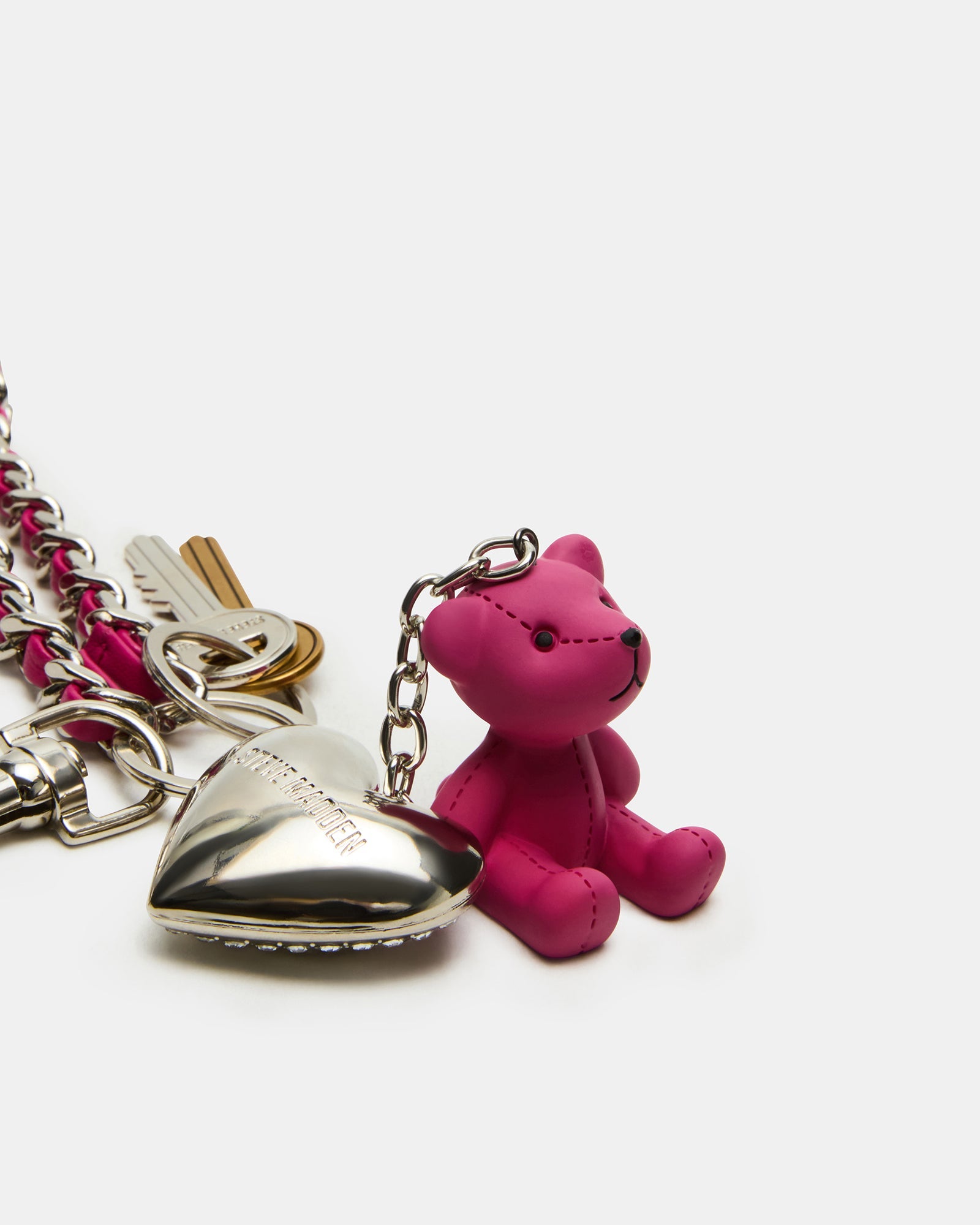 Fuchsia bear charm dangling from a leather bag strap