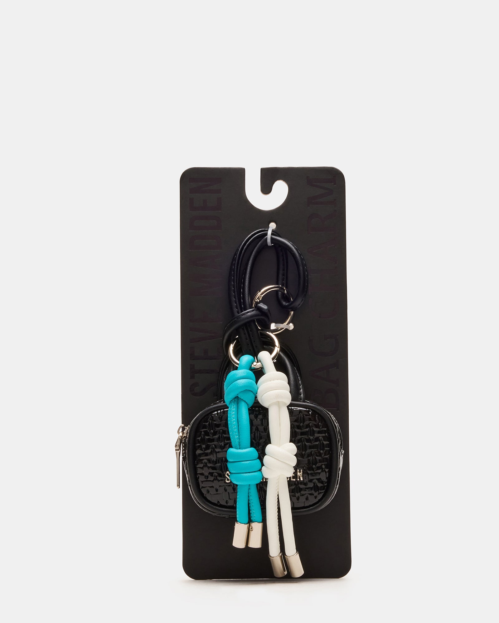 Black bag charm attached to leather tote, shown from side angle in NYC setting
