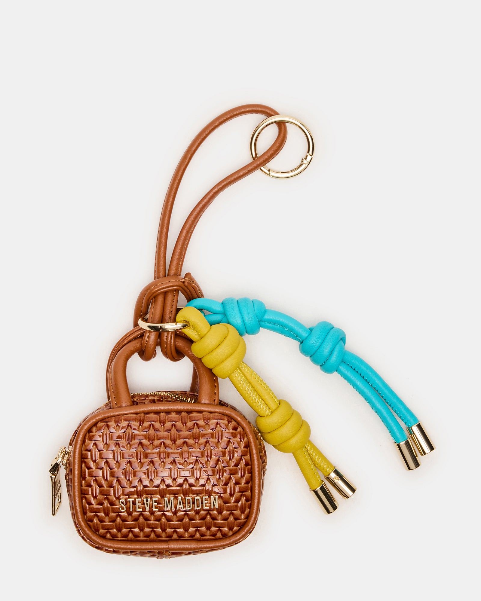 Close-up of cognac mini bag charm clipped to beige crossbody near Boston café