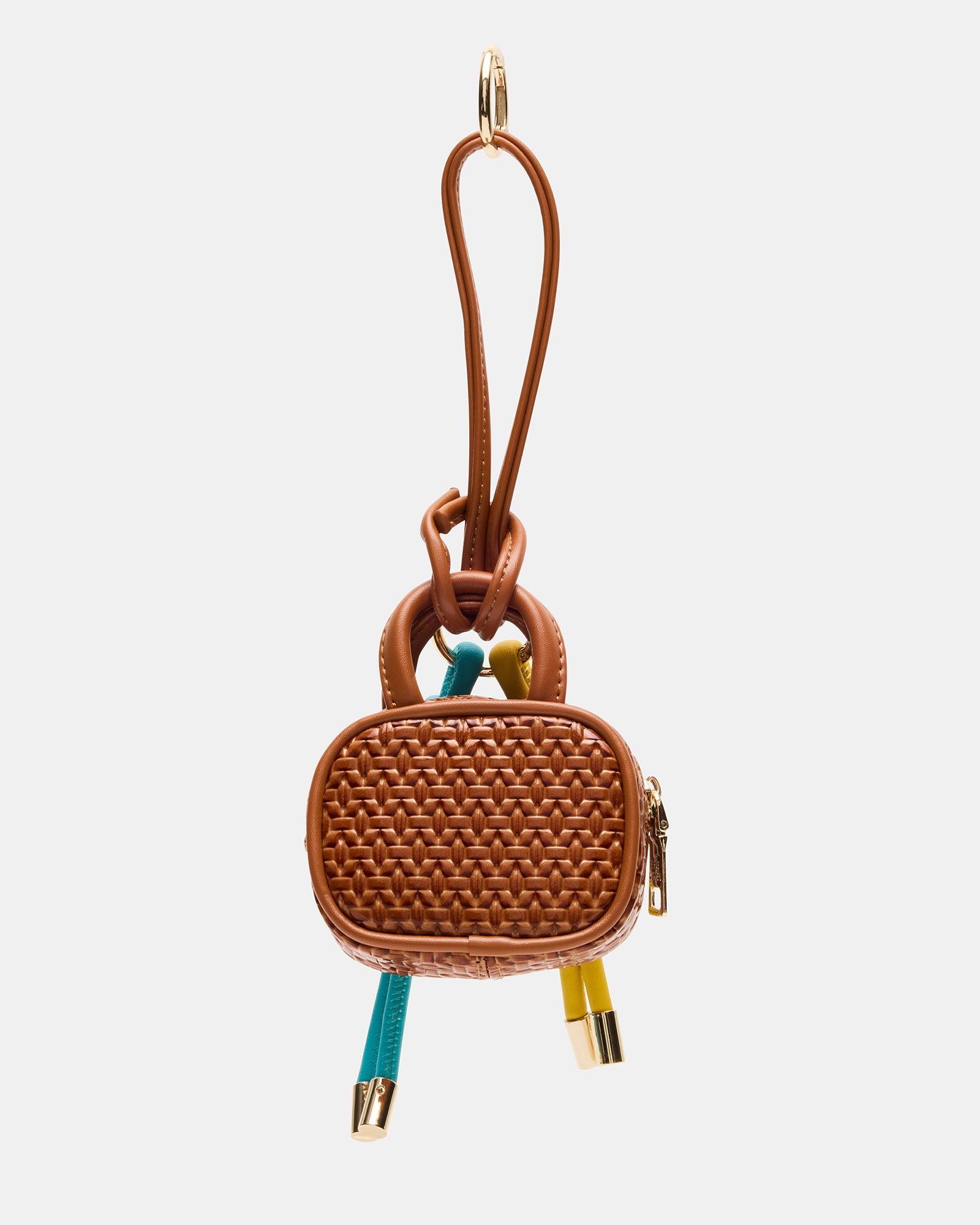 Close-up of cognac mini bag charm clipped to beige crossbody near Boston café