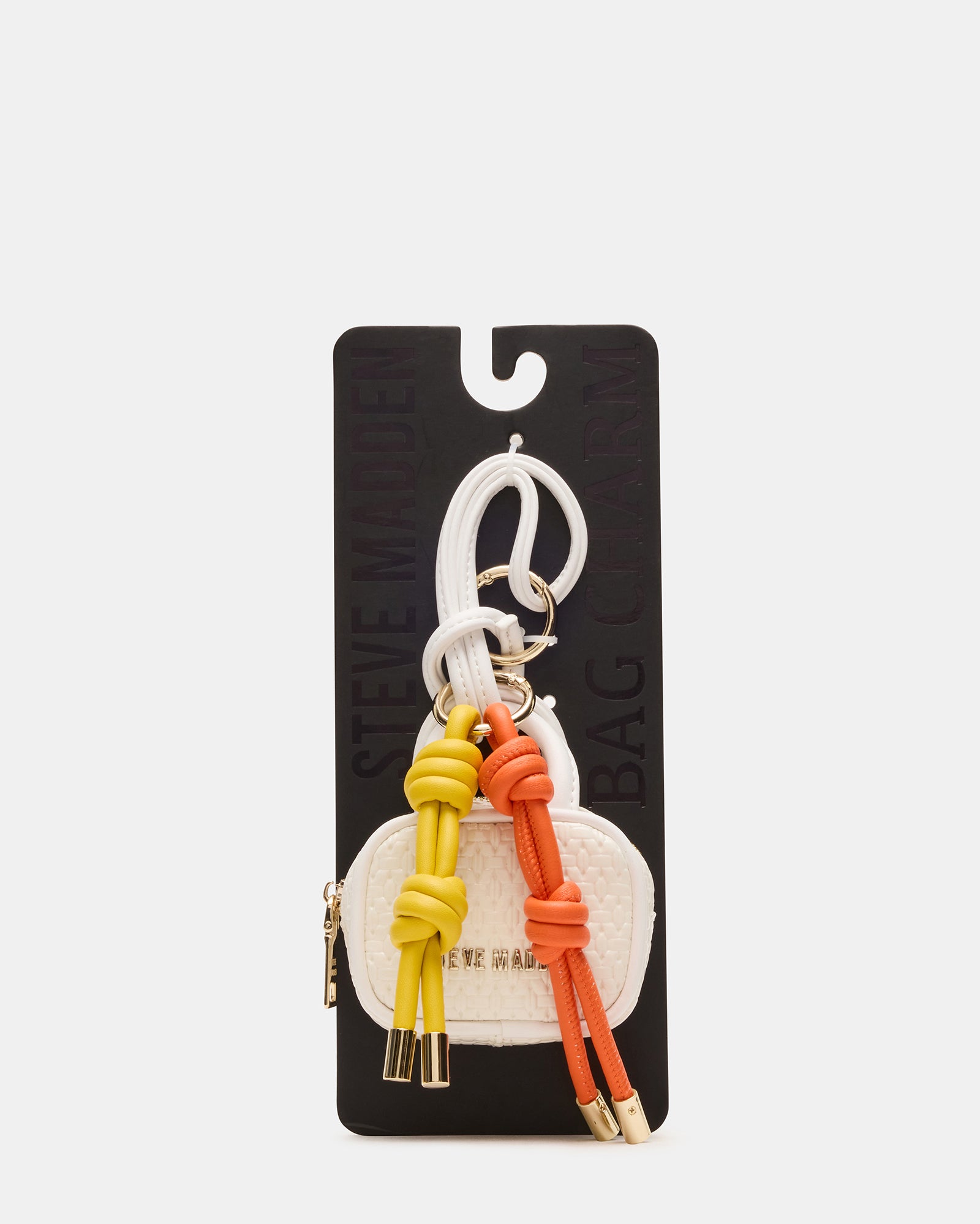 Coach mini bag charm clipped onto leather tote, ideal for city use.