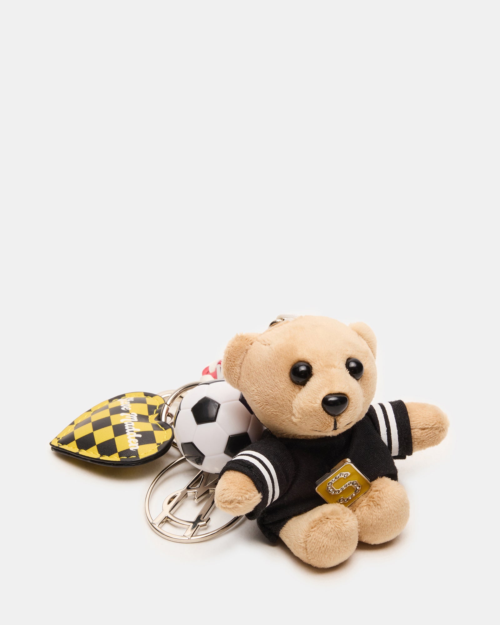 Soccer bear bag charm attached to a backpack in a vibrant outdoor setting.