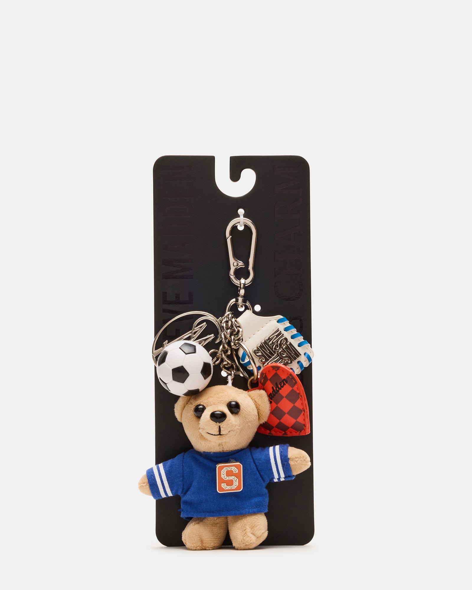 Close-up of stuffed bear holding soccer ball next to metal logo charm
