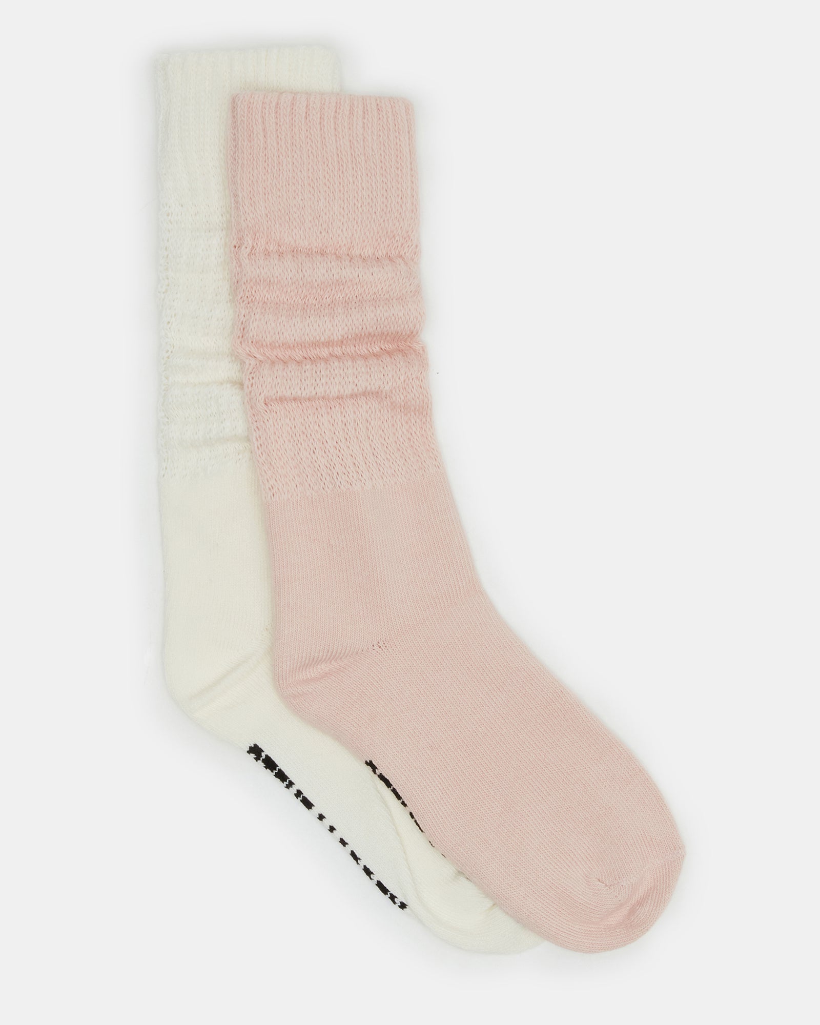 Close-up of ribbed slouchy socks in blush and white tones on a cozy surface