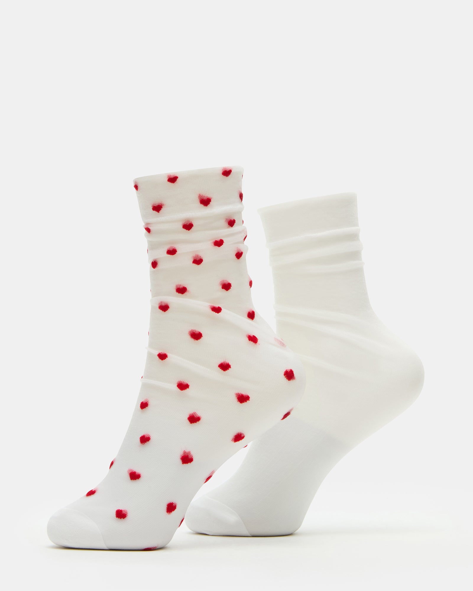 Pair of sheer white ankle socks with heart design displayed on a wooden surface