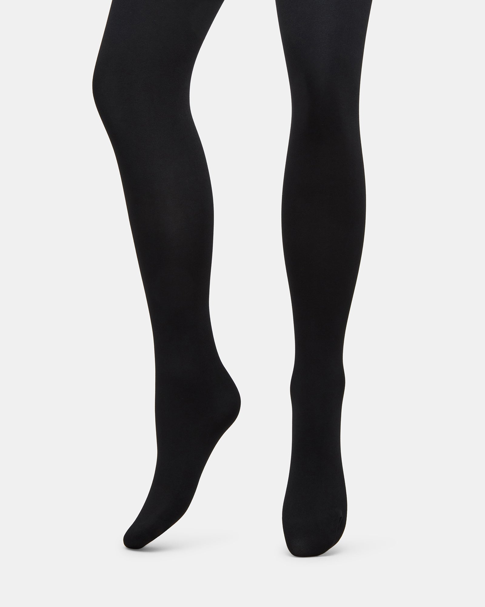 Front view of black shaping tights styled with a fitted blouse
