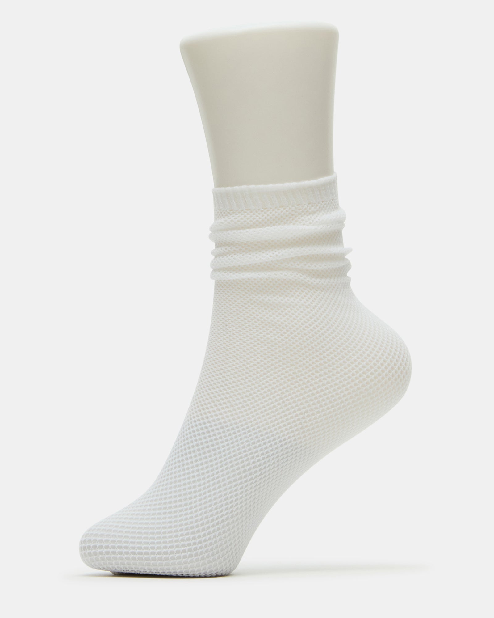 Front angle of slouchy white socks worn with low-top sneakers on a city sidewalk