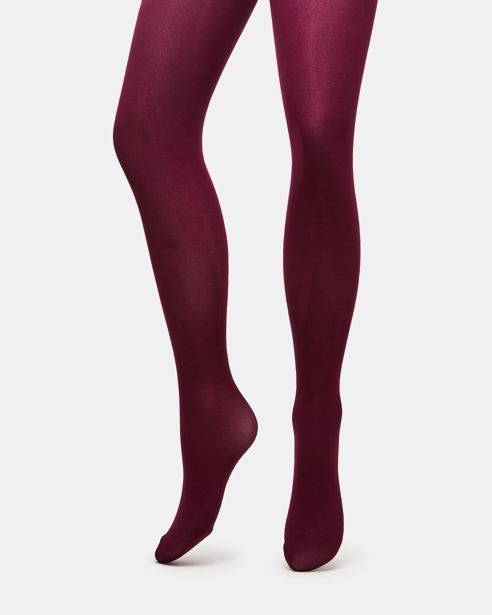 Side view of BerryFlex footed tights styled with boots on urban sidewalk