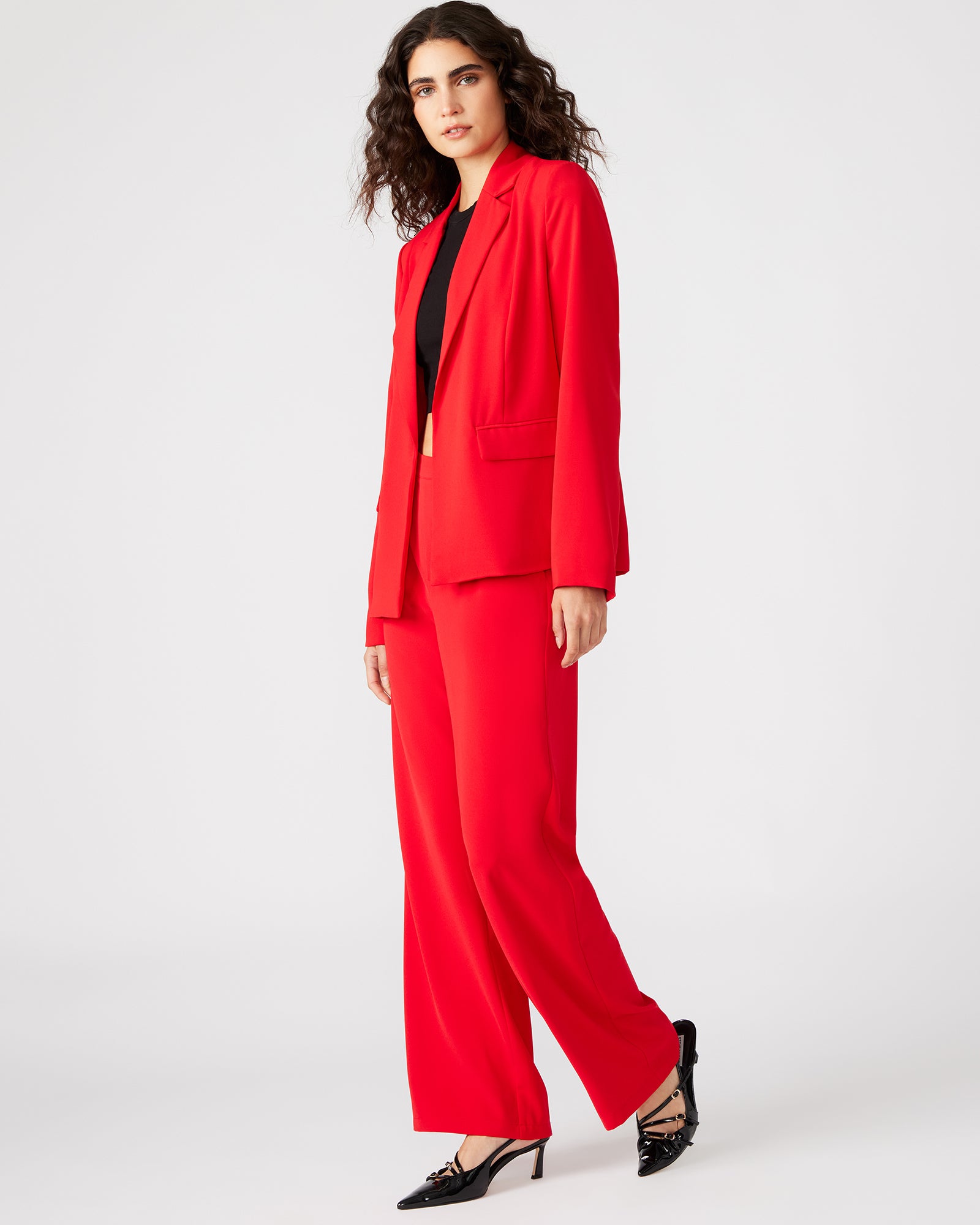 Detail shot of notched lapel and open cuffs on womens blazer, styled with minimal accessories.