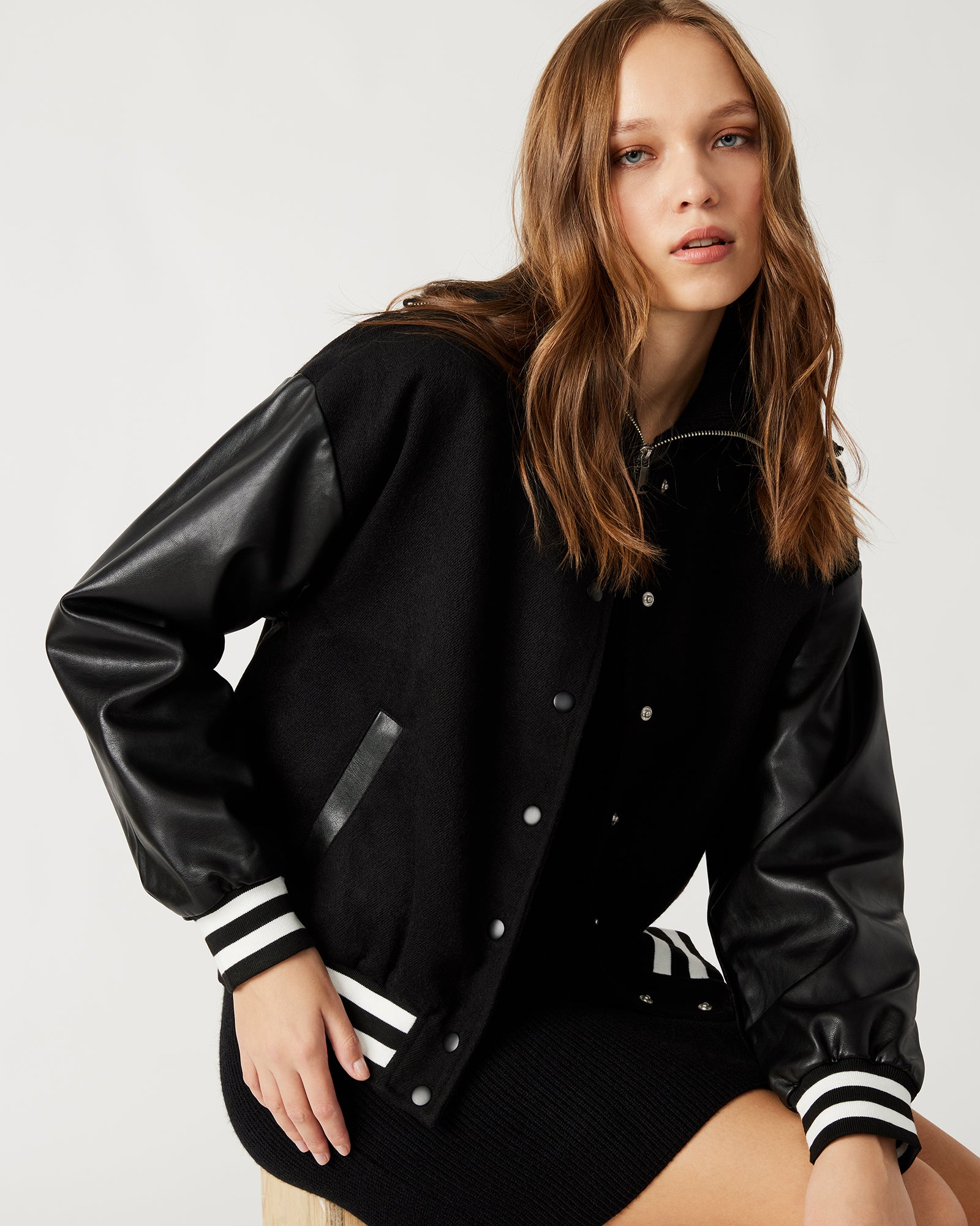 Side profile of the vegan leather sleeve varsity jacket in black