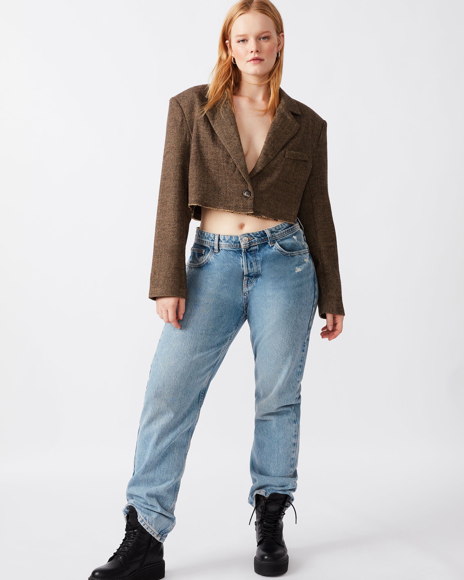 Model wearing cropped tweed blazer with rolled sleeves in urban setting