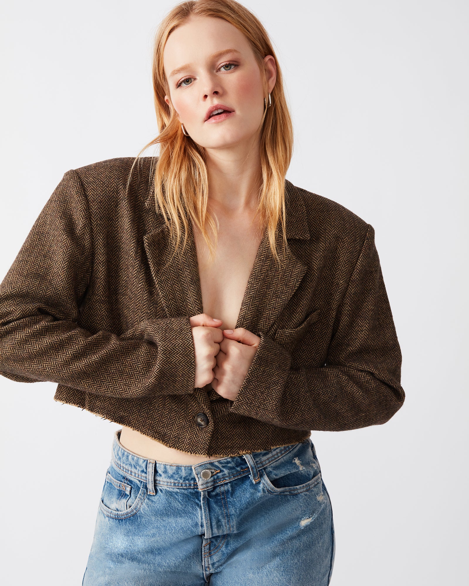 Model wearing cropped tweed blazer with rolled sleeves in urban setting