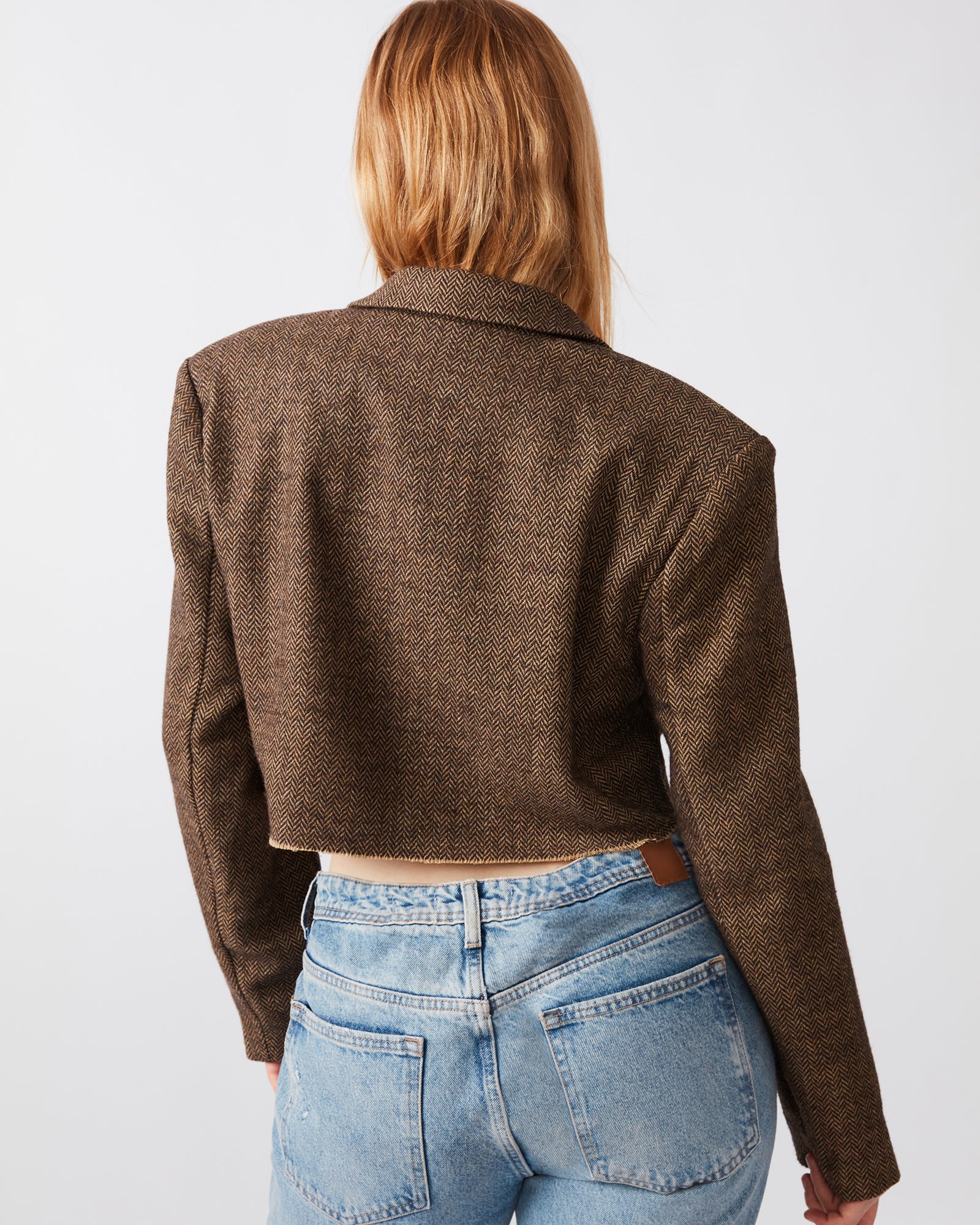 Back view showing raw hem design of cropped black blazer