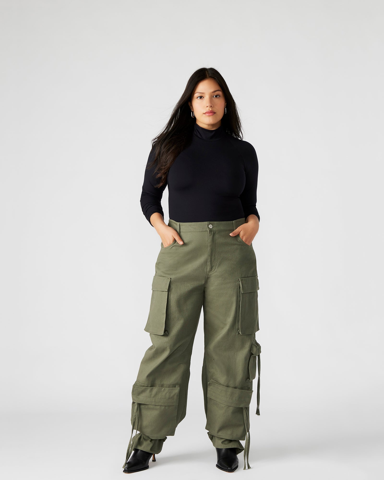 Close-up of cargo pockets and zipper pulls on DUO olive pants