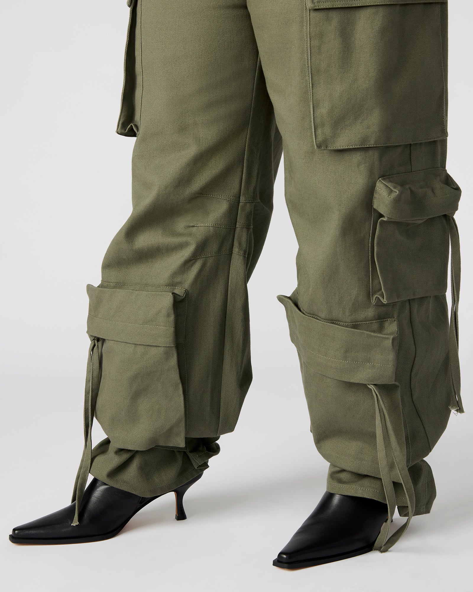 Close-up of cargo pockets and zipper pulls on DUO olive pants