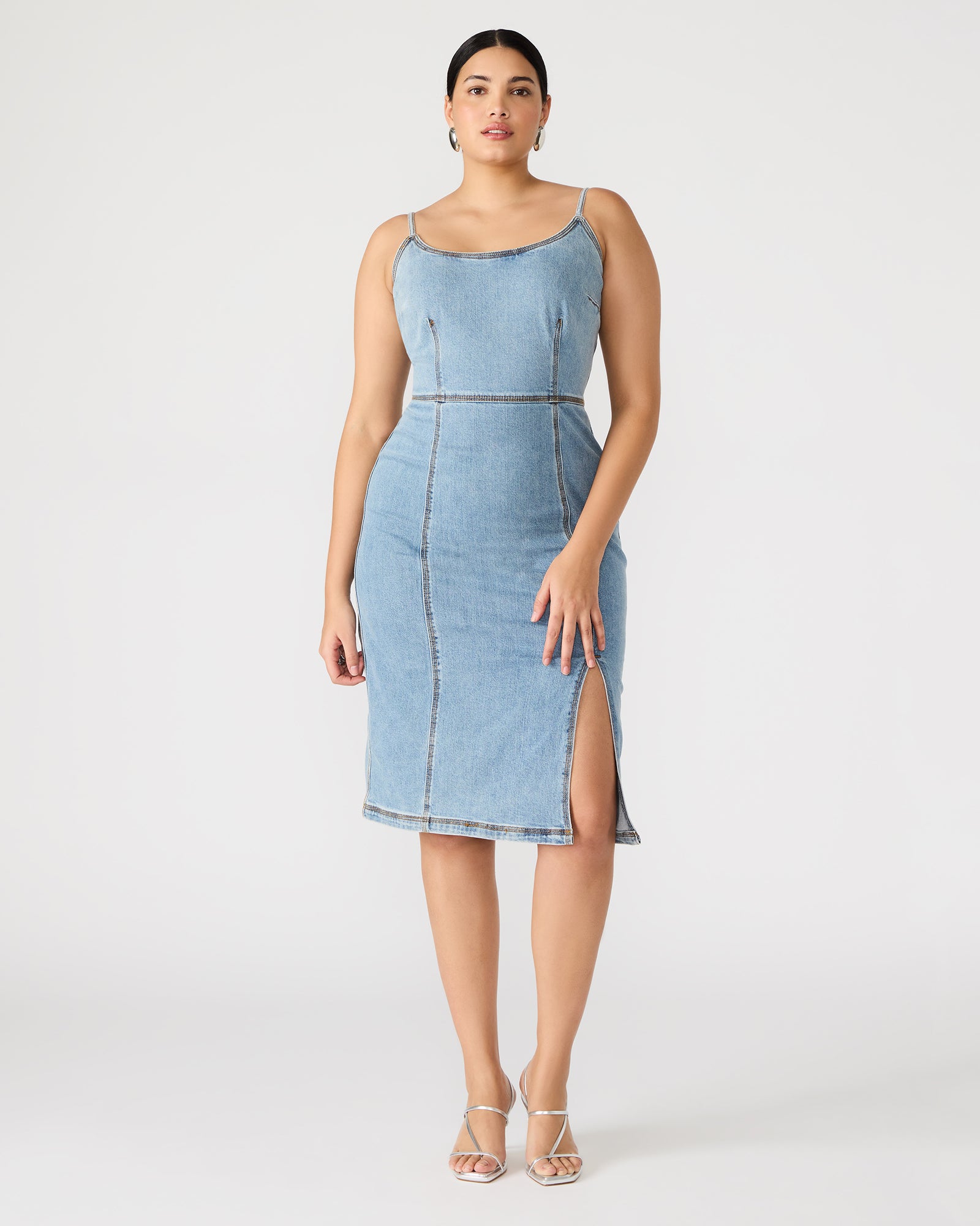 Woman wearing blue denim midi dress with crossbody bag in city setting