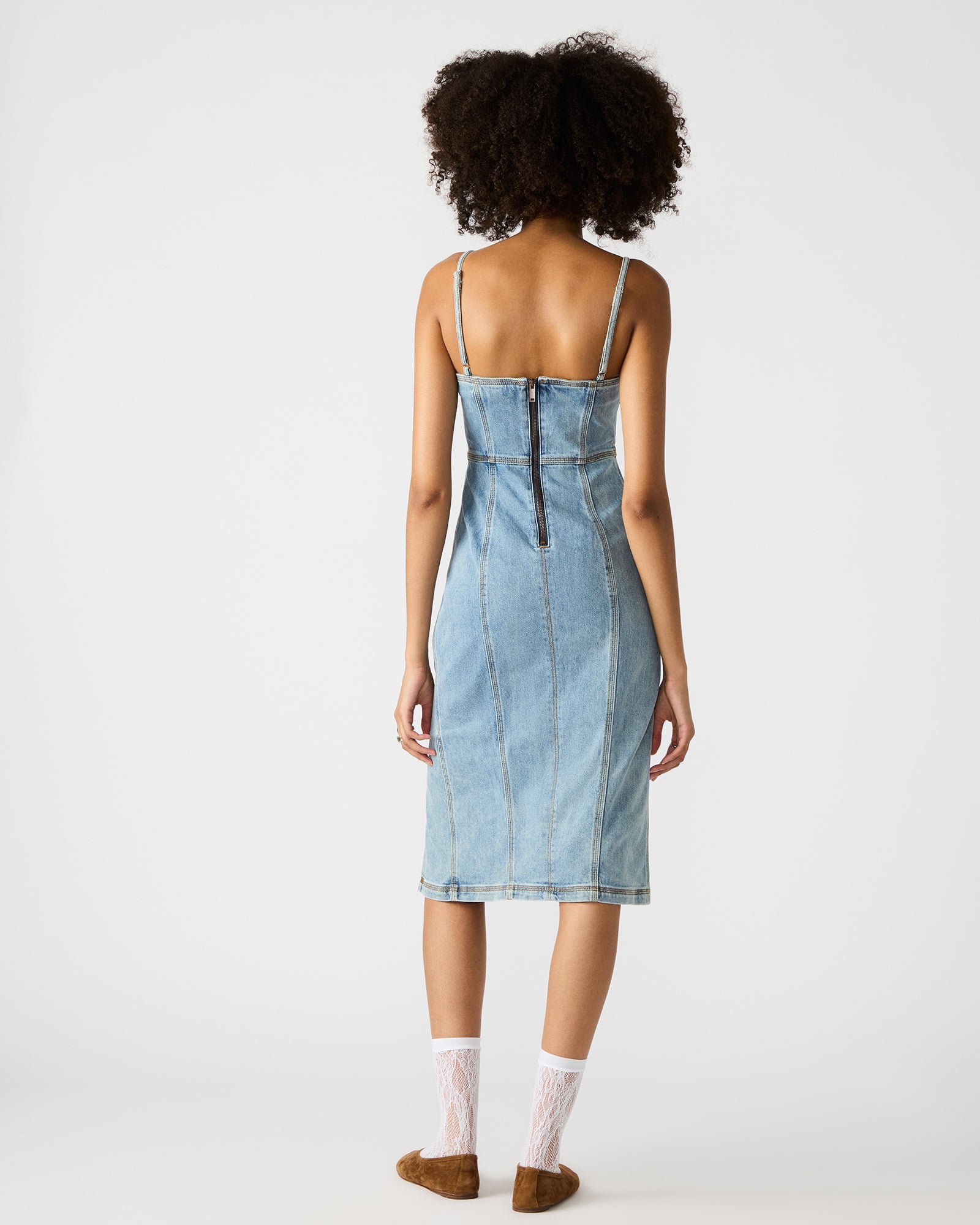 Woman wearing blue denim midi dress with crossbody bag in city setting