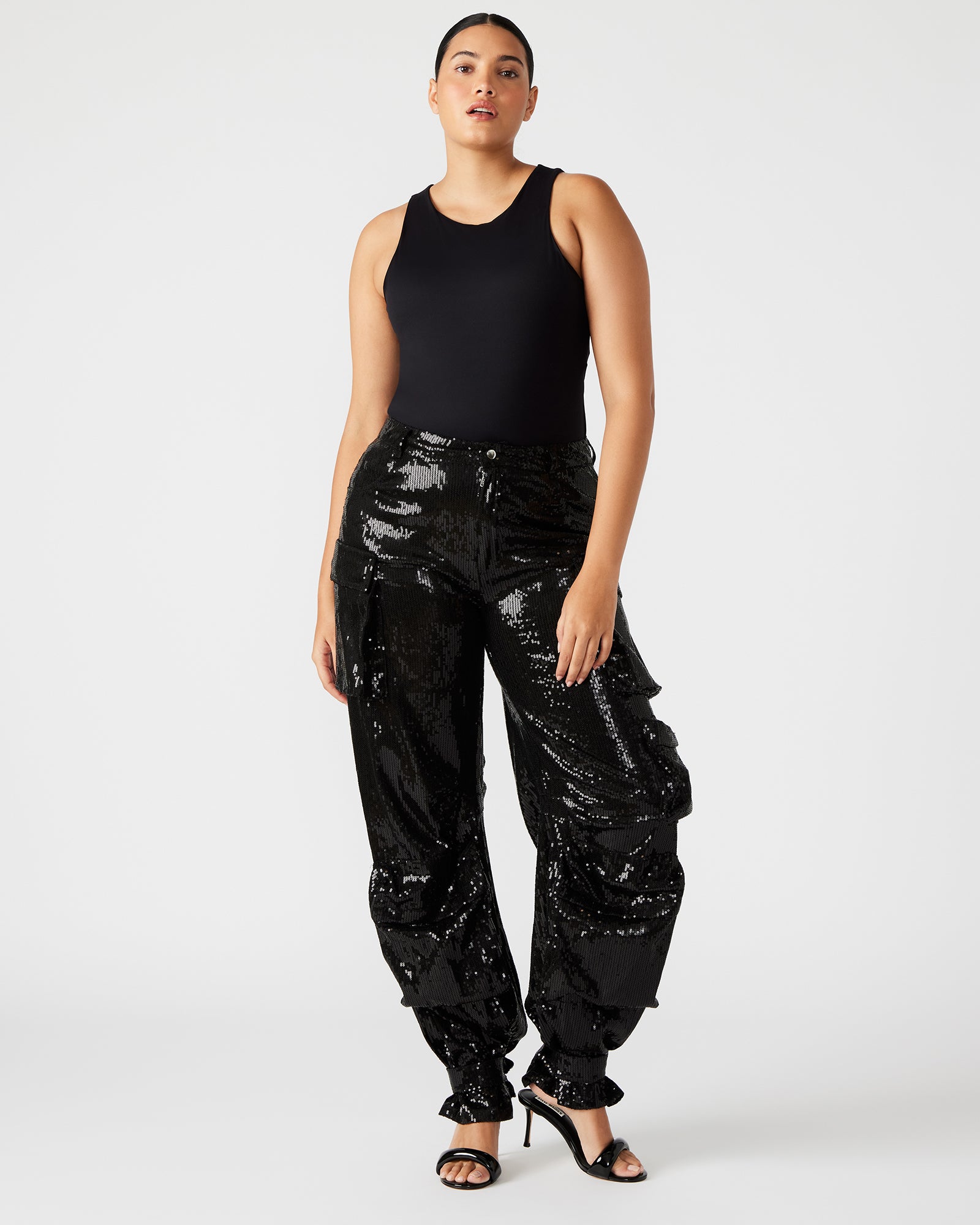 Side view of black cargo pants styled with ankle strap detail in urban Chicago setting.