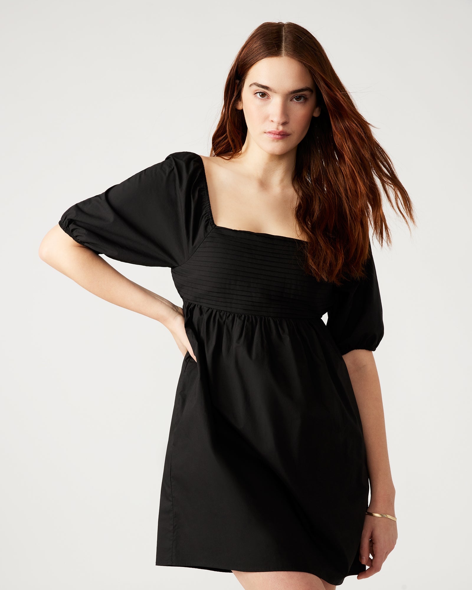 Woman pairing the elegant black dress with accessories for a night out