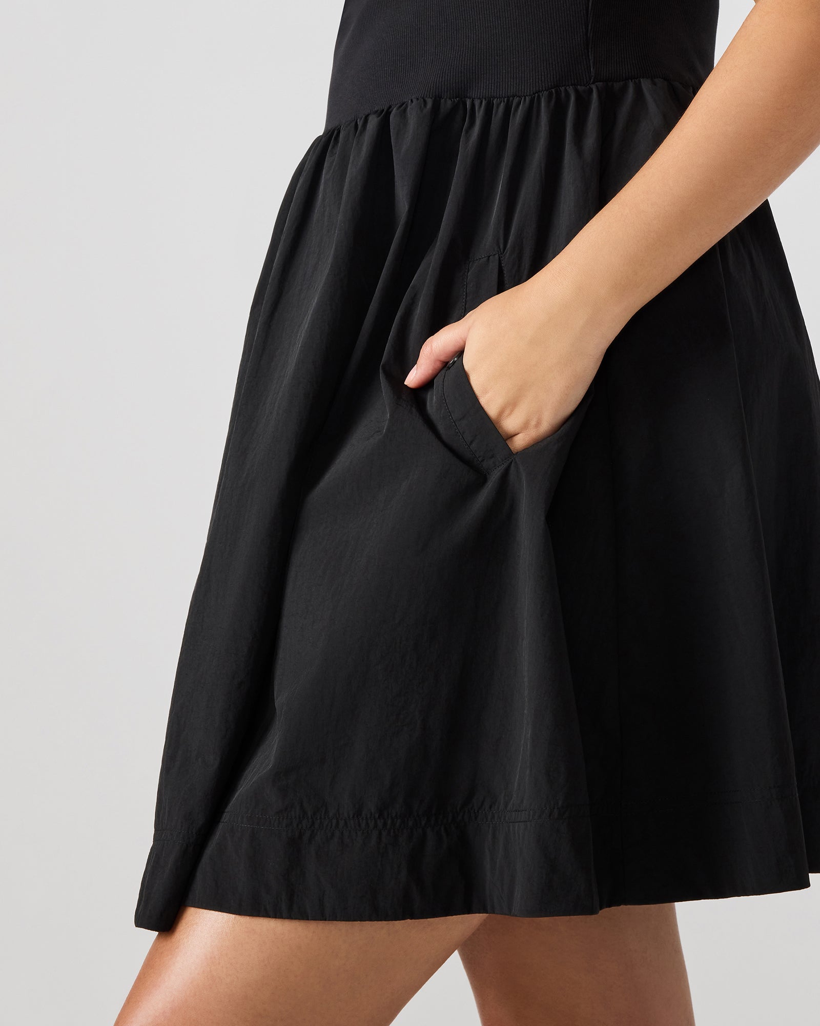 Side angle showing tank-style top and snap pockets on black ruffle dress