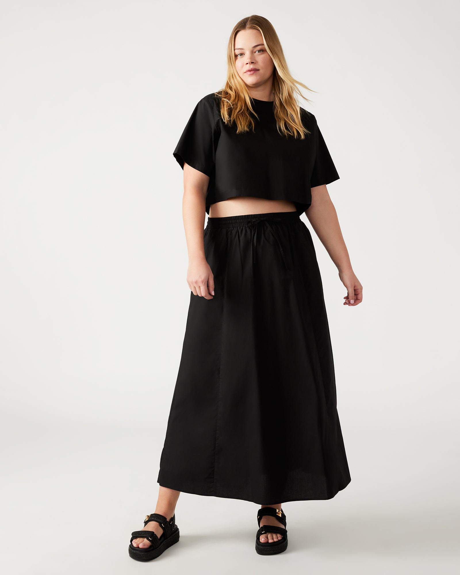 Close-up of the black maxi skirt's side pockets and front tie detail