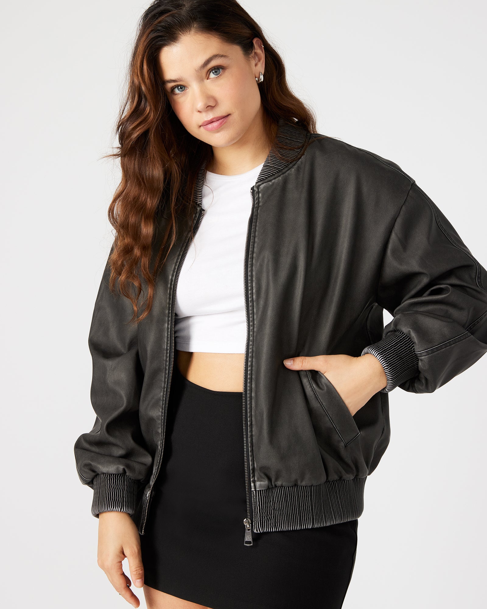 Front view of oversized faux leather jacket paired with denim on urban backdrop