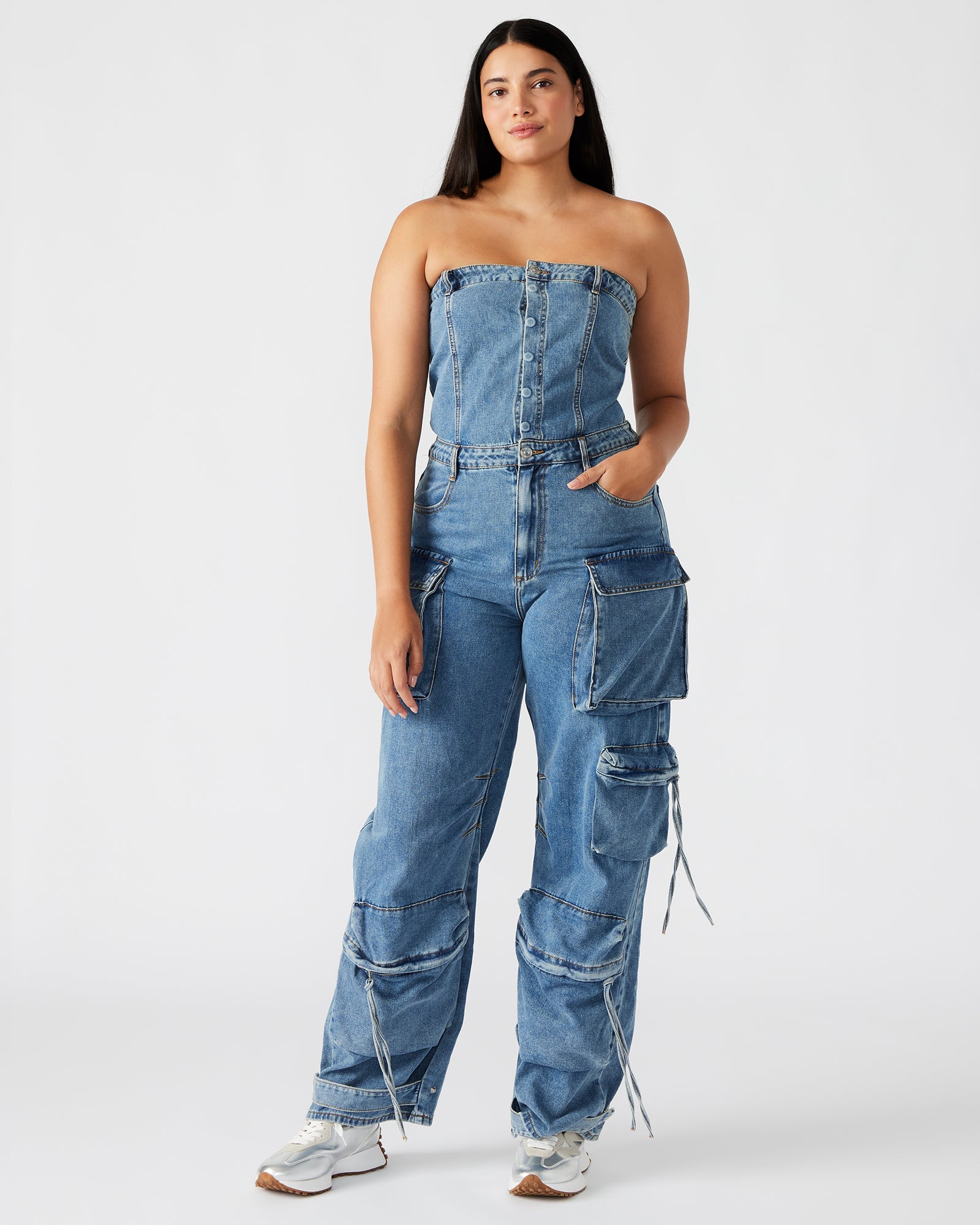 Model styling the black denim jumpsuit with ankle straps in an urban setting