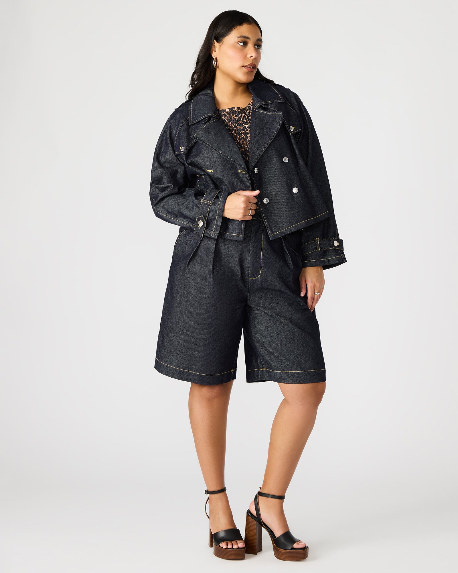 Front view of cropped indigo denim jacket showcasing double-breasted design.