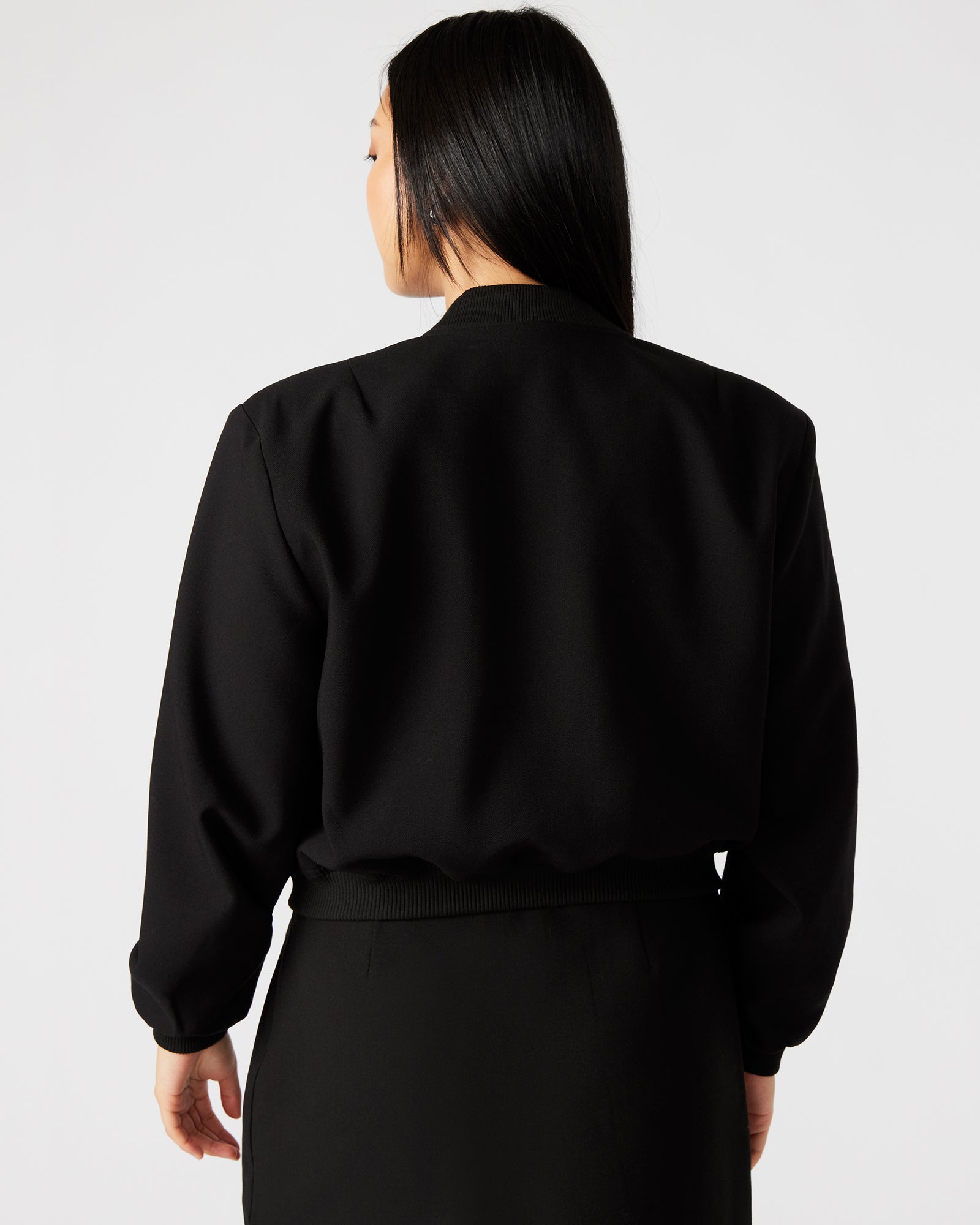 Front view of stylish black leather bomber jacket on model.
