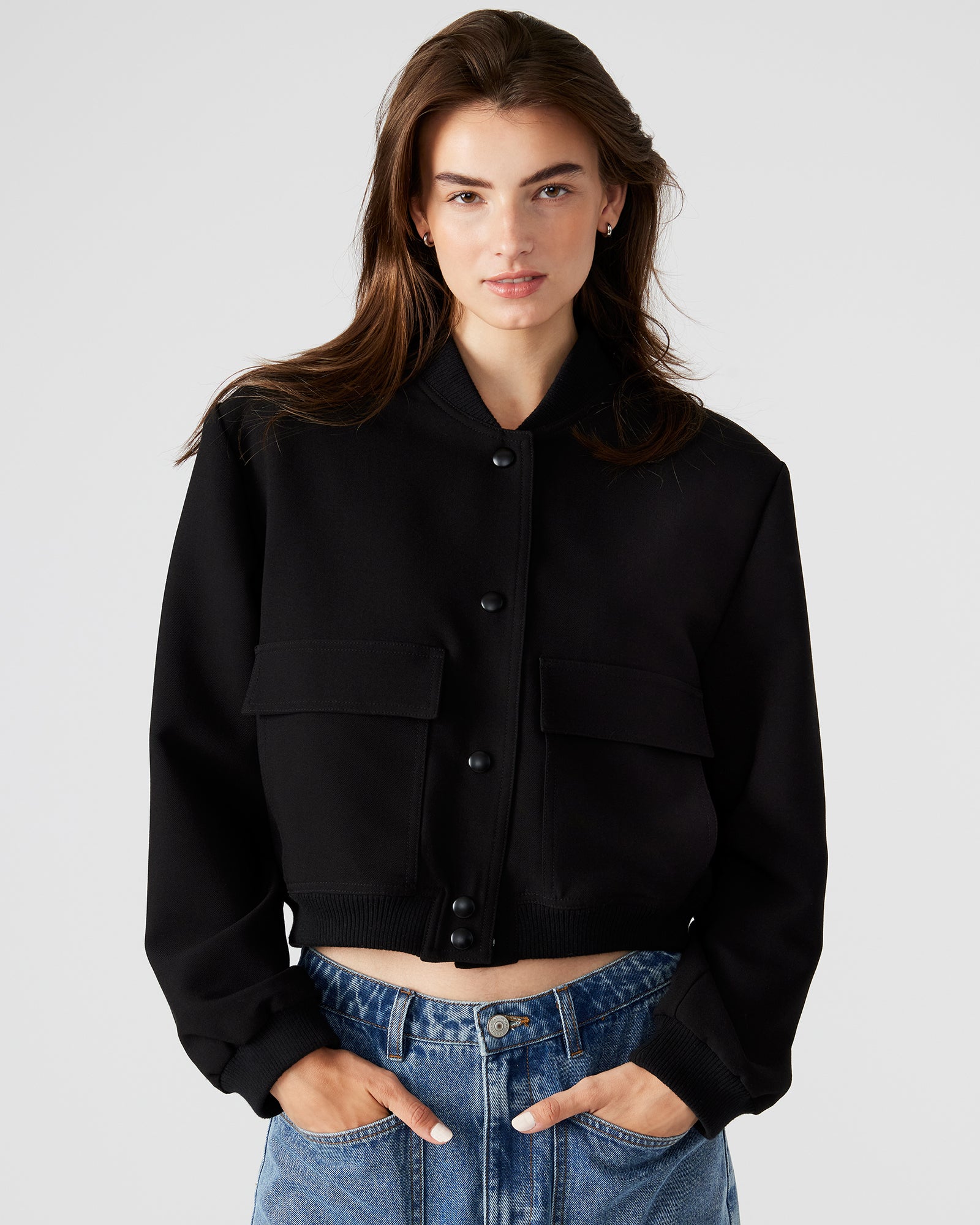 Front view of stylish black leather bomber jacket on model.
