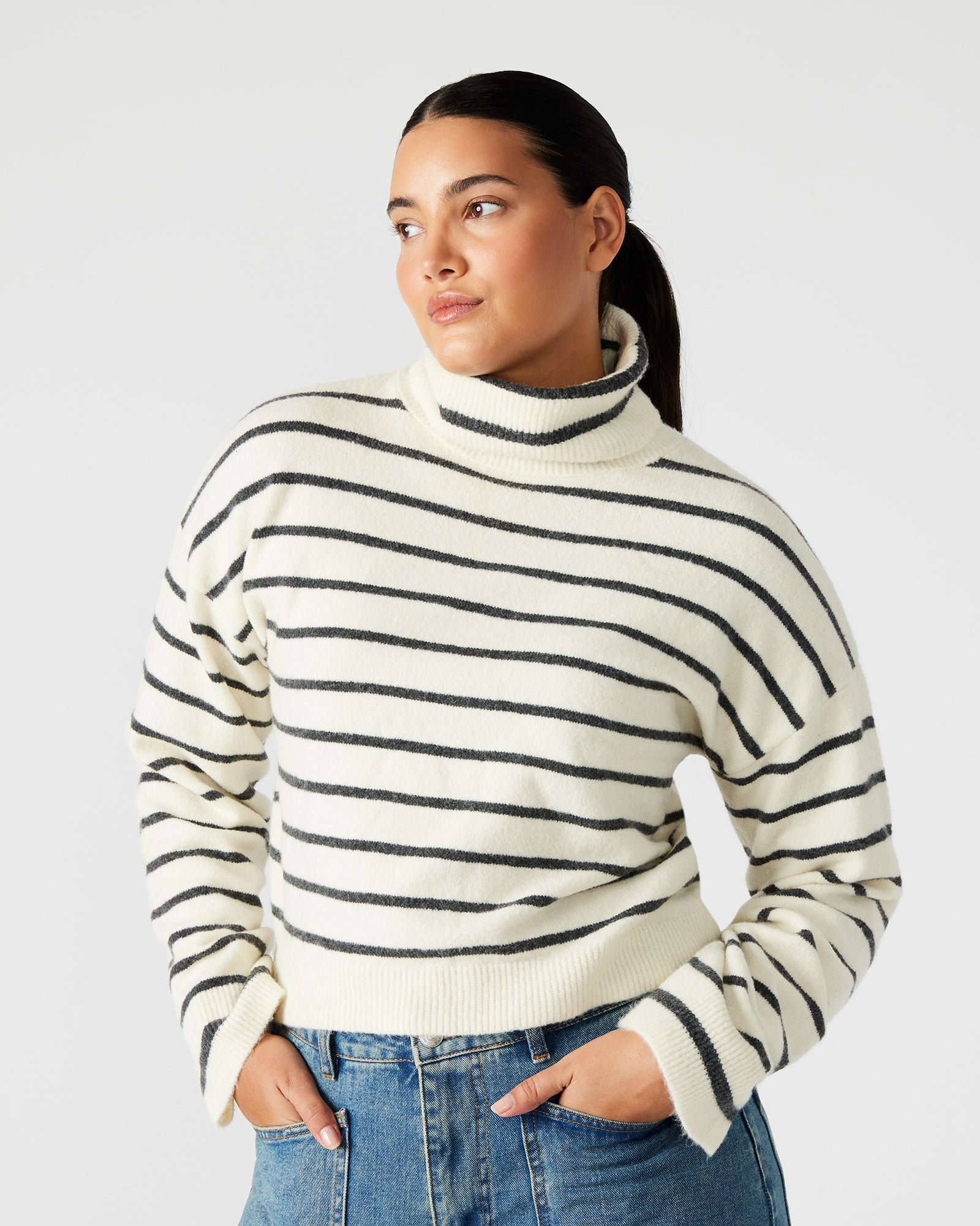 Model wearing the striped turtleneck sweater, paired with jeans for a stylish look.