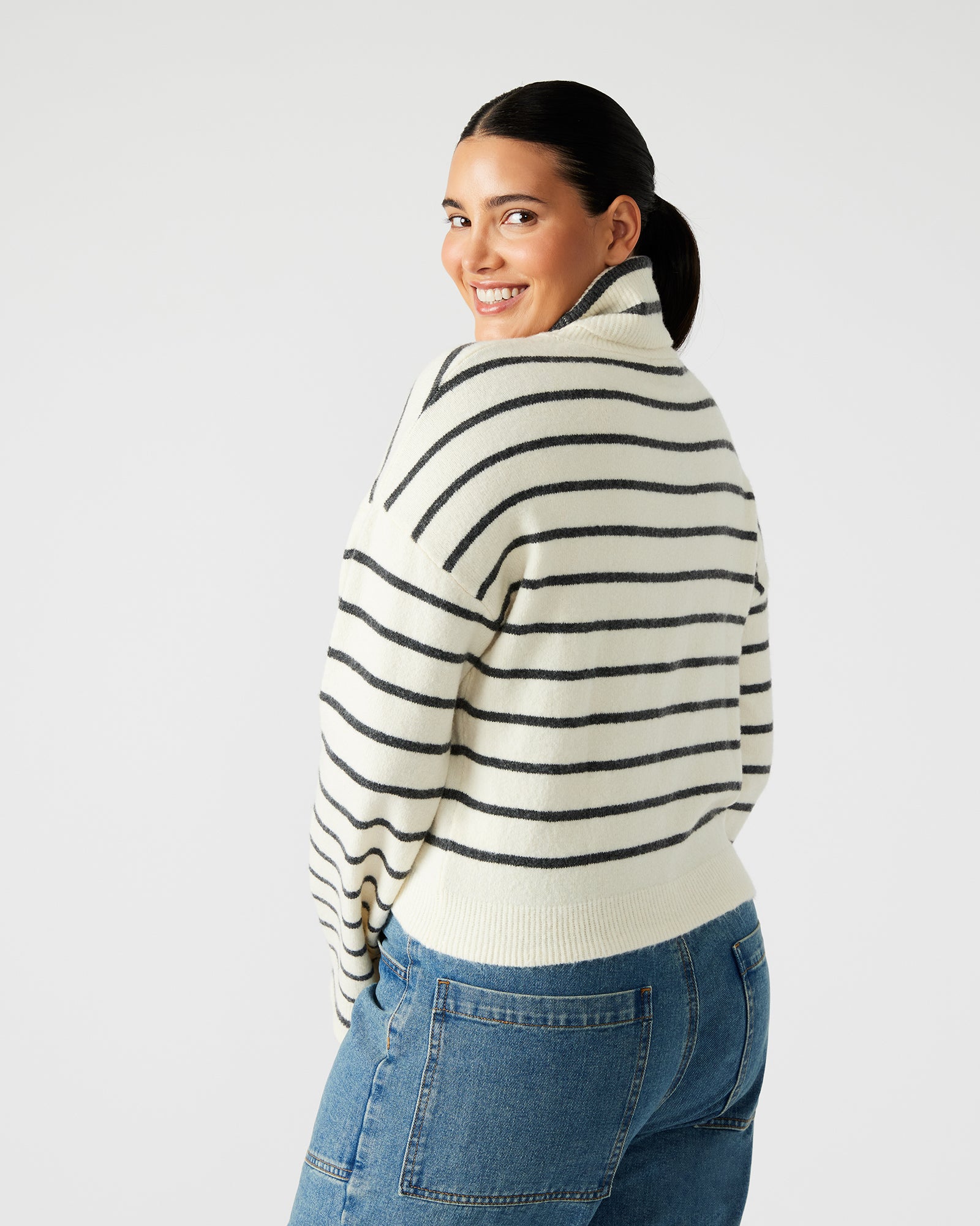 Close-up of the fabric texture of the black and white striped turtleneck sweater.