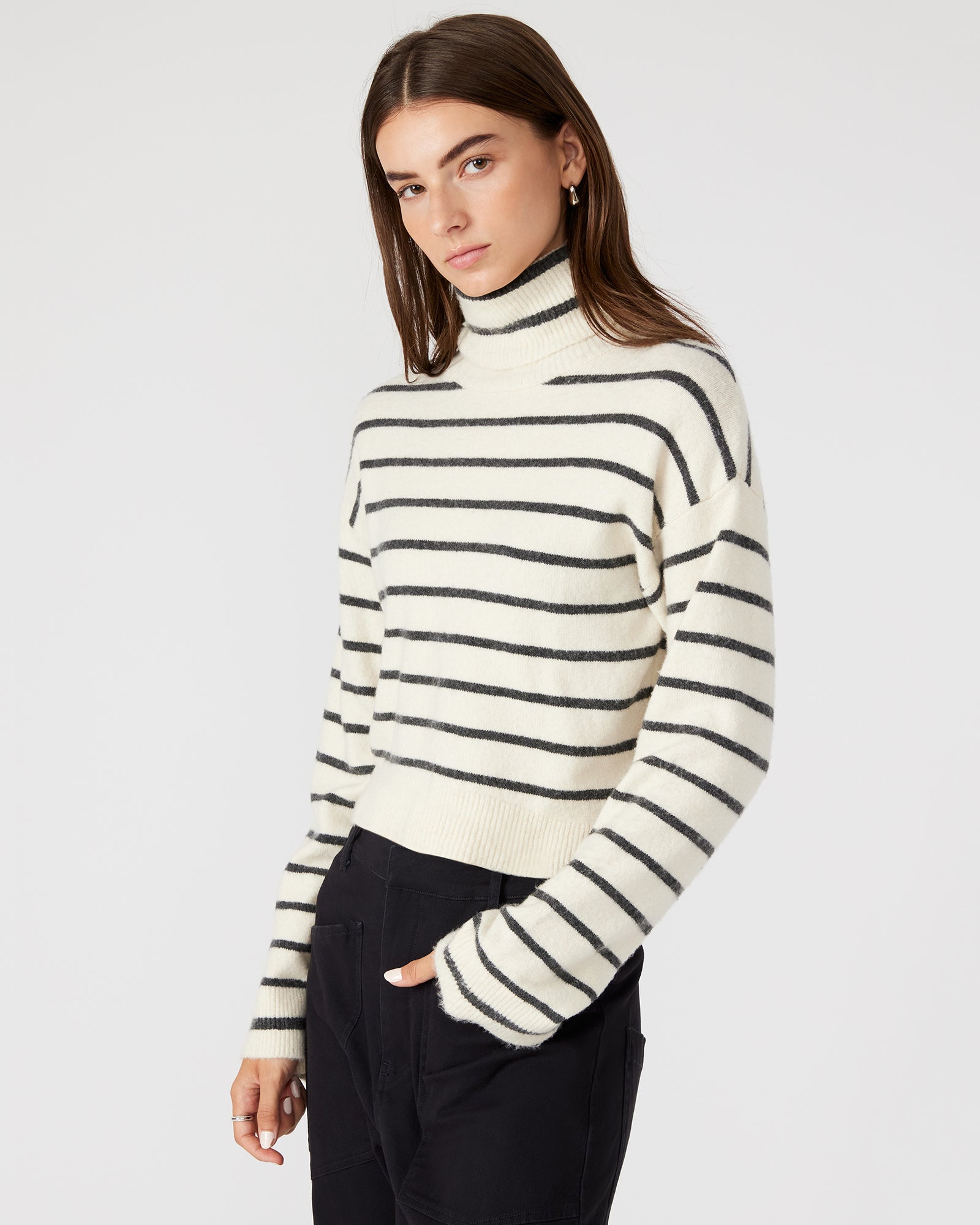Front view of the chic black and white striped turtleneck sweater, showcasing flare sleeves.