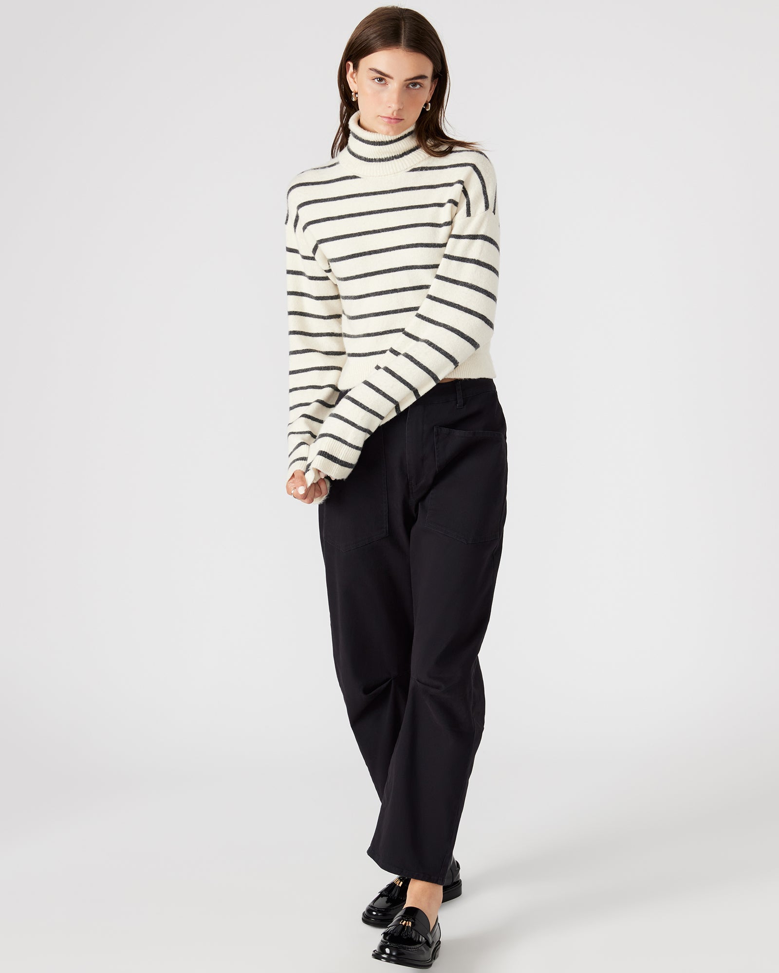 Model wearing the striped turtleneck sweater, paired with jeans for a stylish look.