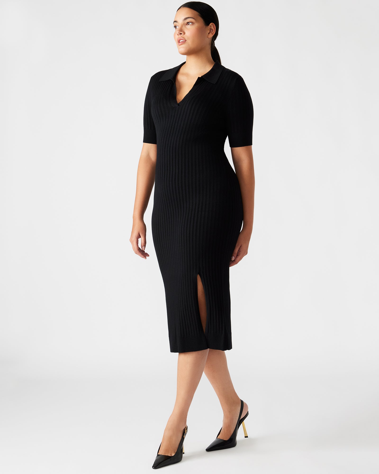 Full shot of a woman wearing a fitted black dress with collar detail, suitable for black tie wedding guest attire.