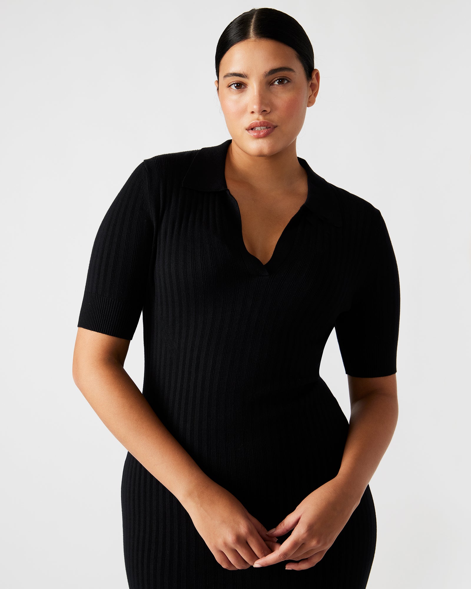 Model walking confidently in a black dress with a front slit, ideal for formal occasions.