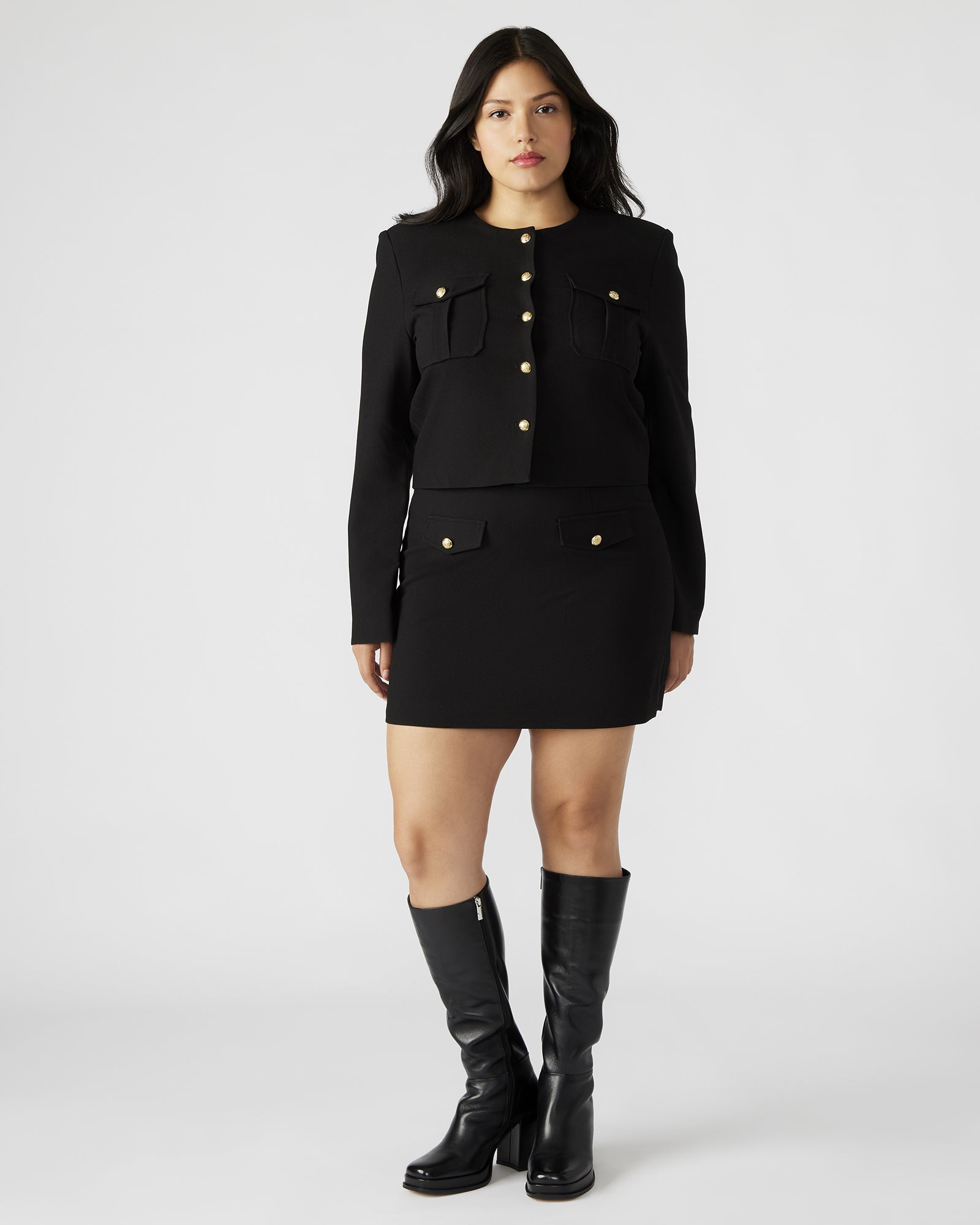 Side view of the black leather mini skirt with crest buttons.