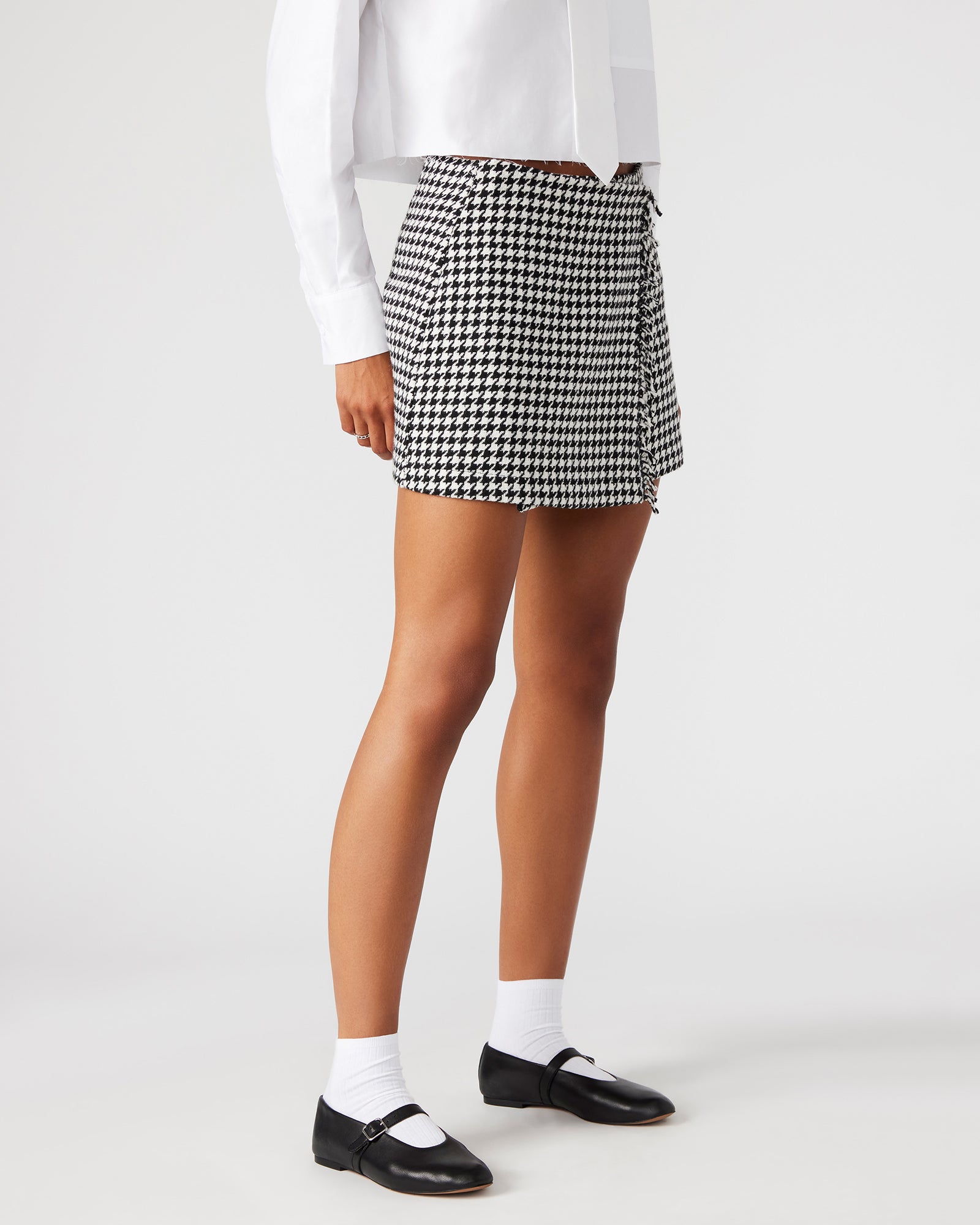 Close-up of tweed wrap skirt waist and fringe overlay in black and white