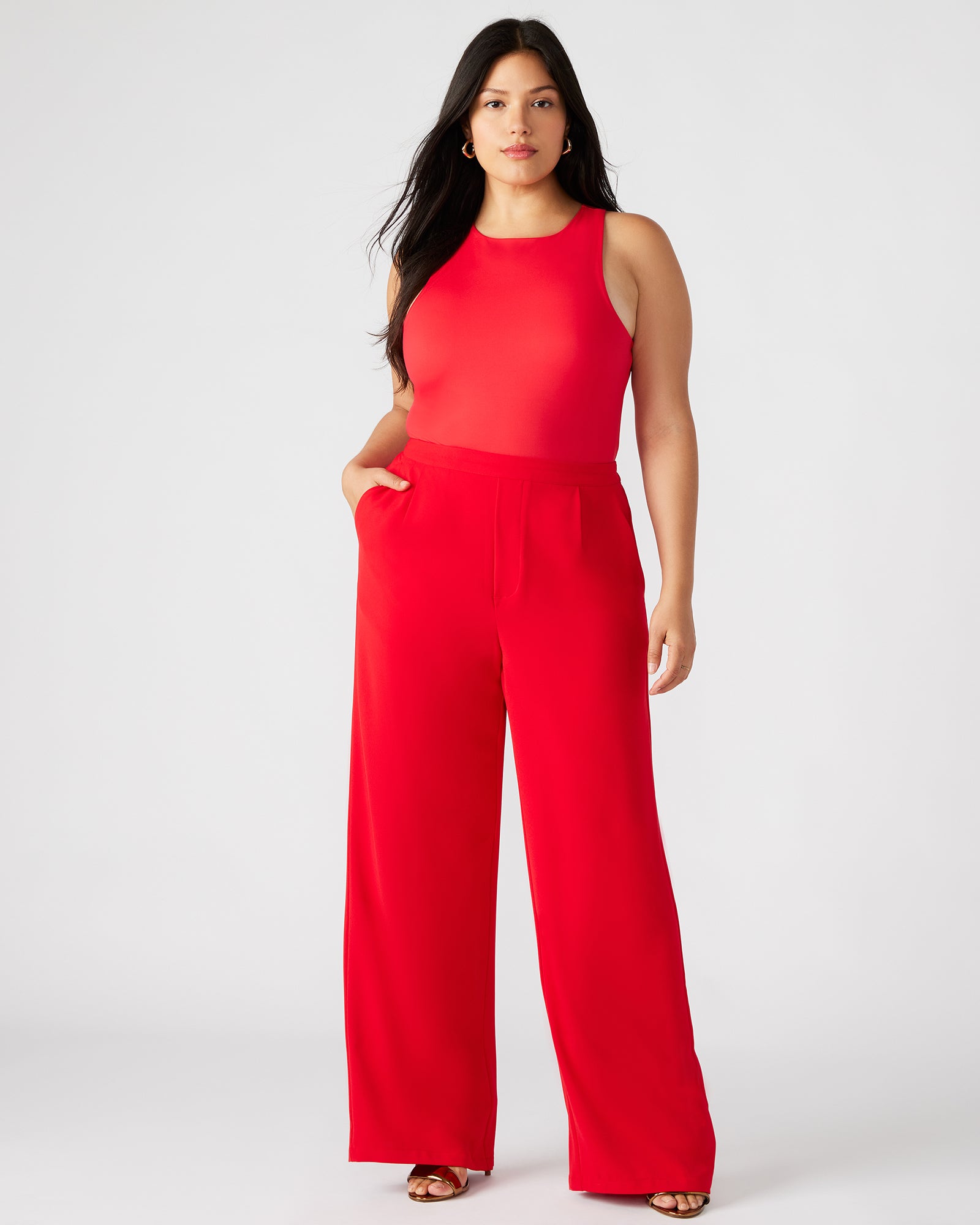 Close-up of the vibrant red wide leg trousers showcasing pleat details.