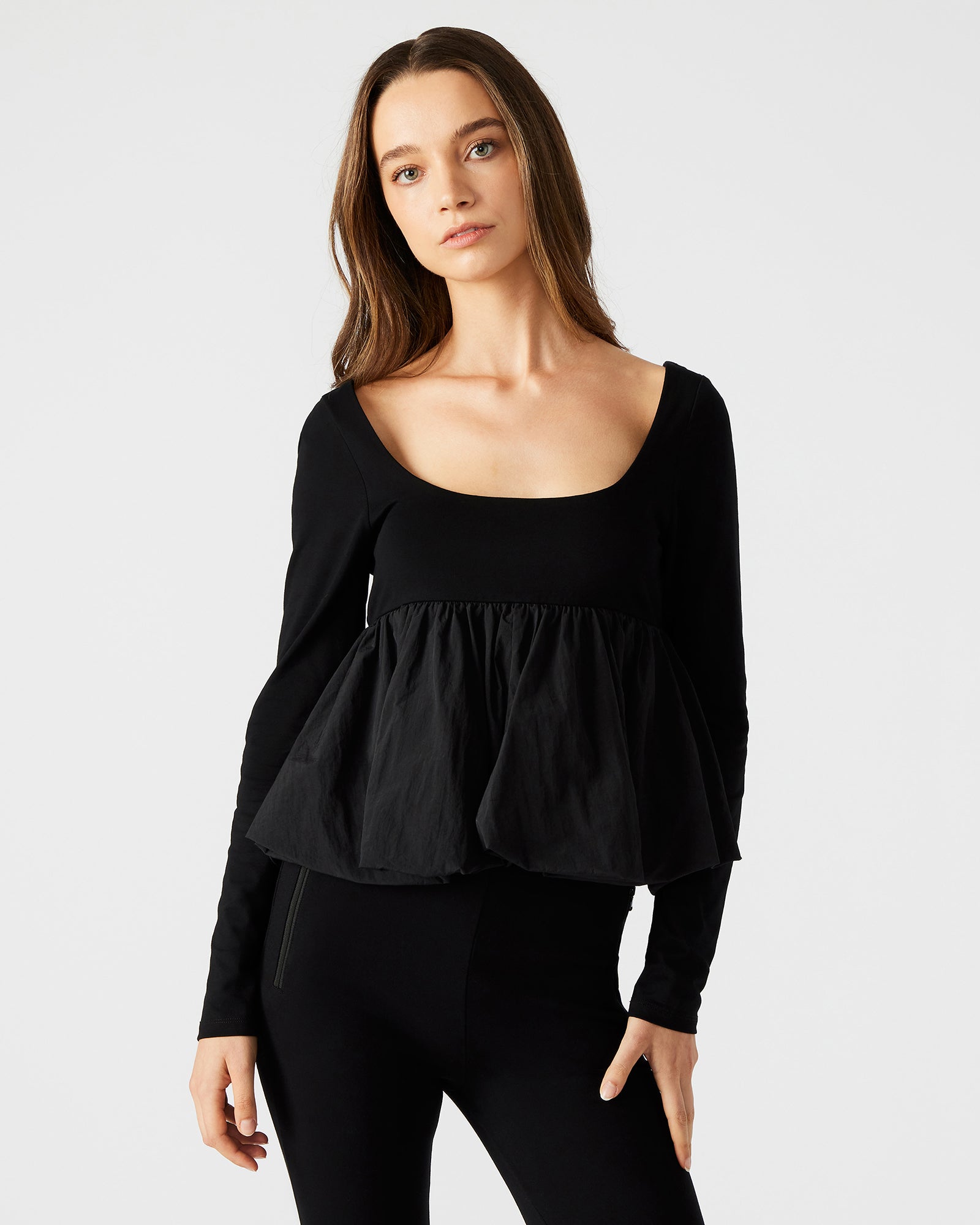 Black peplum top laid flat, showcasing the bubble hem design